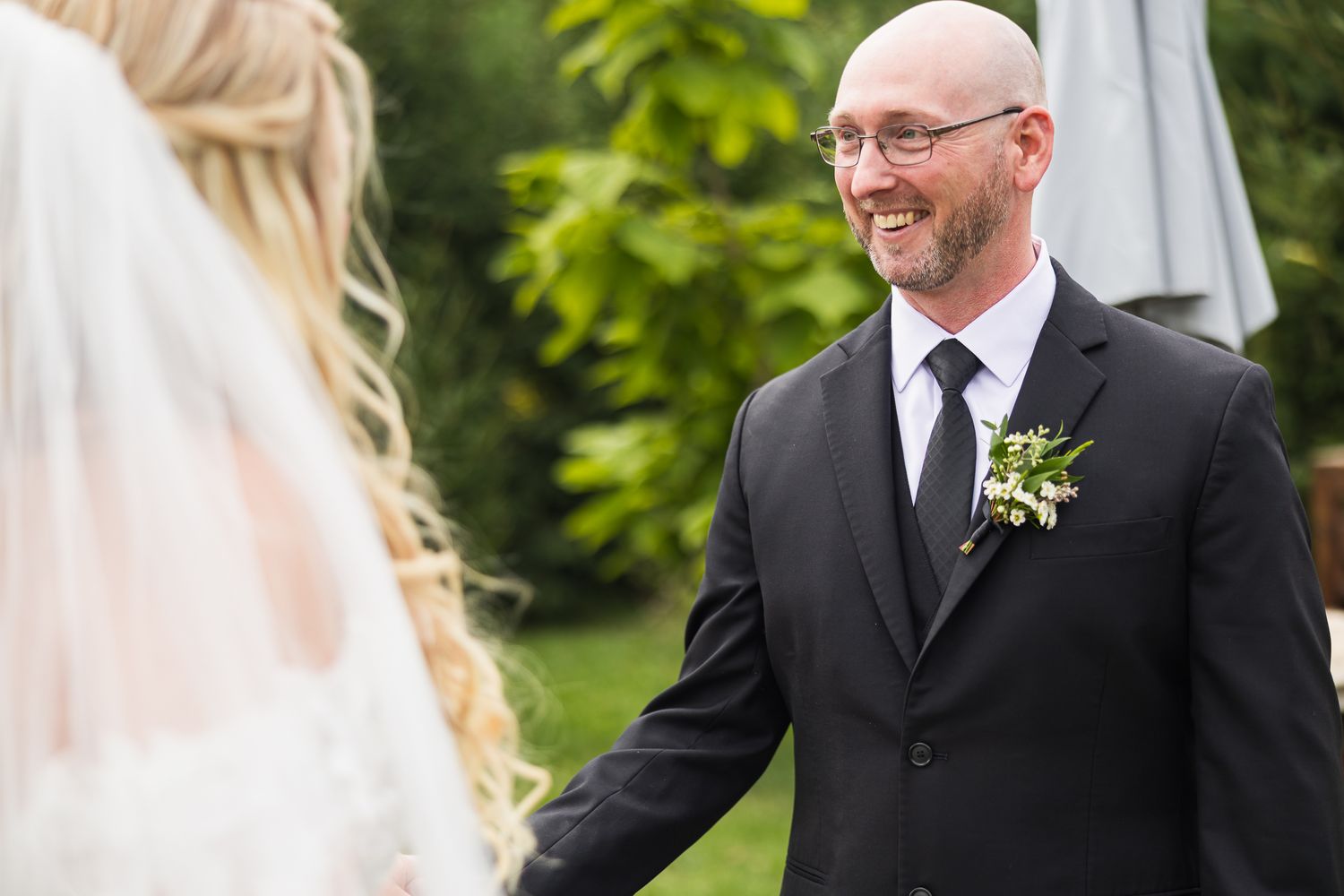 An intimate wedding ceremony moment captured in a sunlit outdoor garden setting.
