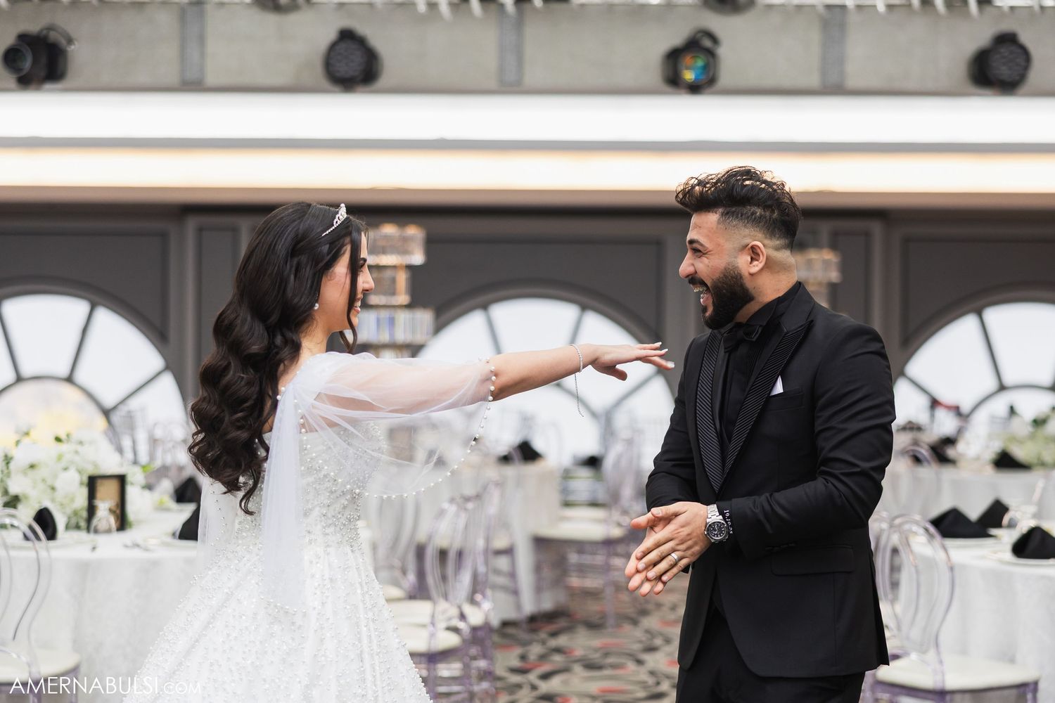 Bride and groom share emotional first look reaction in an elegant white-decorated venue.