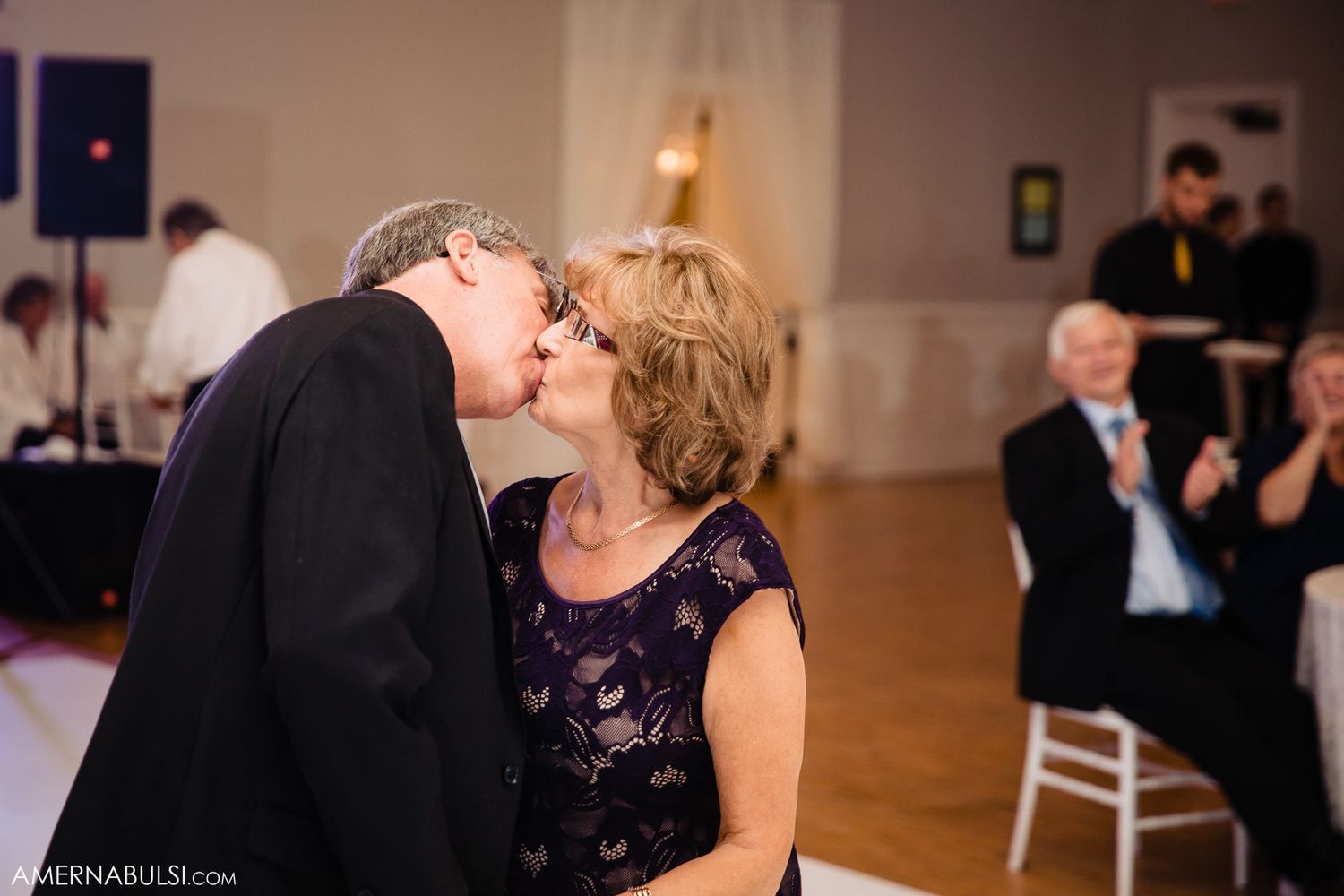Couples dancing together at an elegant wedding reception in a ballroom with warm lighting.
