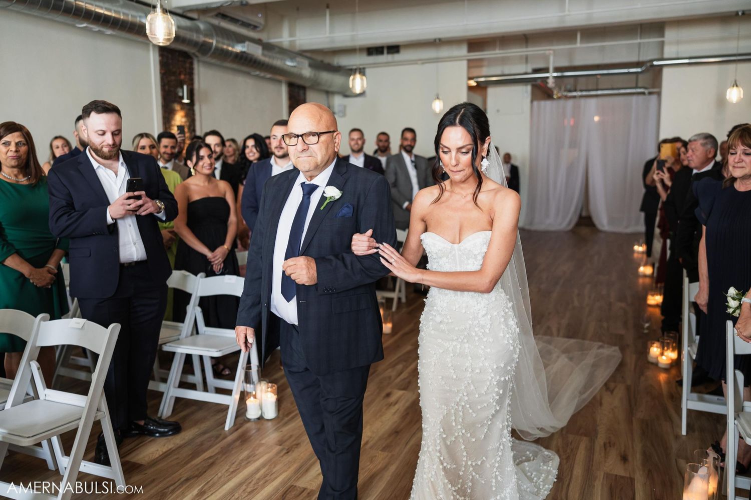 Wedding party and guests sharing candid moment during ceremony in modern loft space.
