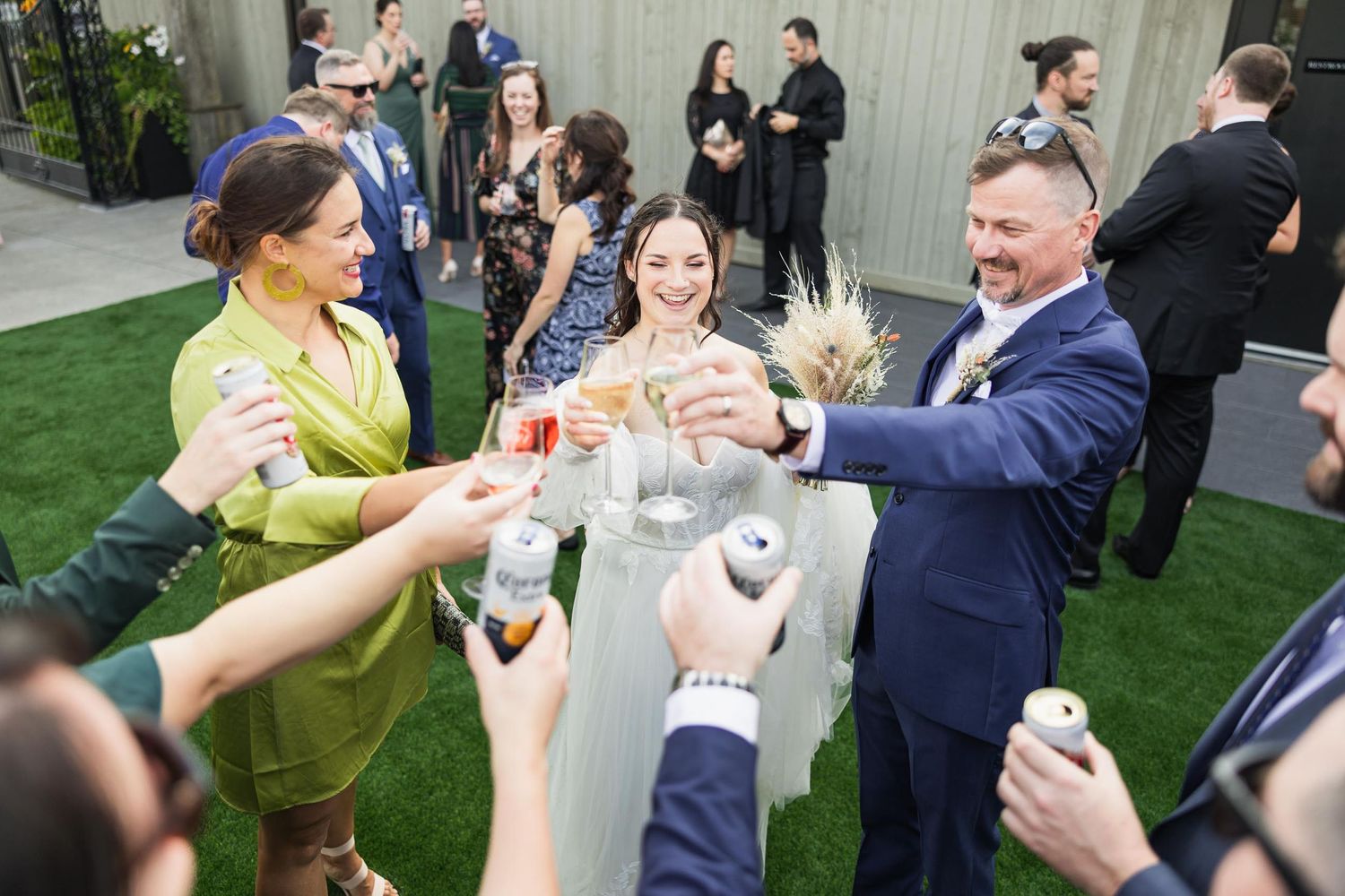 Wedding guests toasting with drinks during outdoor reception celebration.