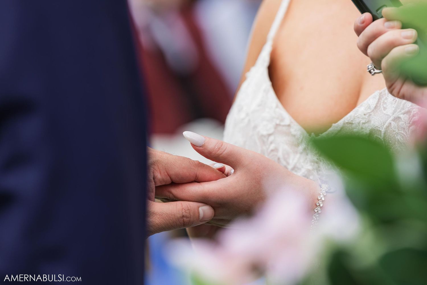 Close-up shot of wedding rings being exchanged during outdoor ceremony.