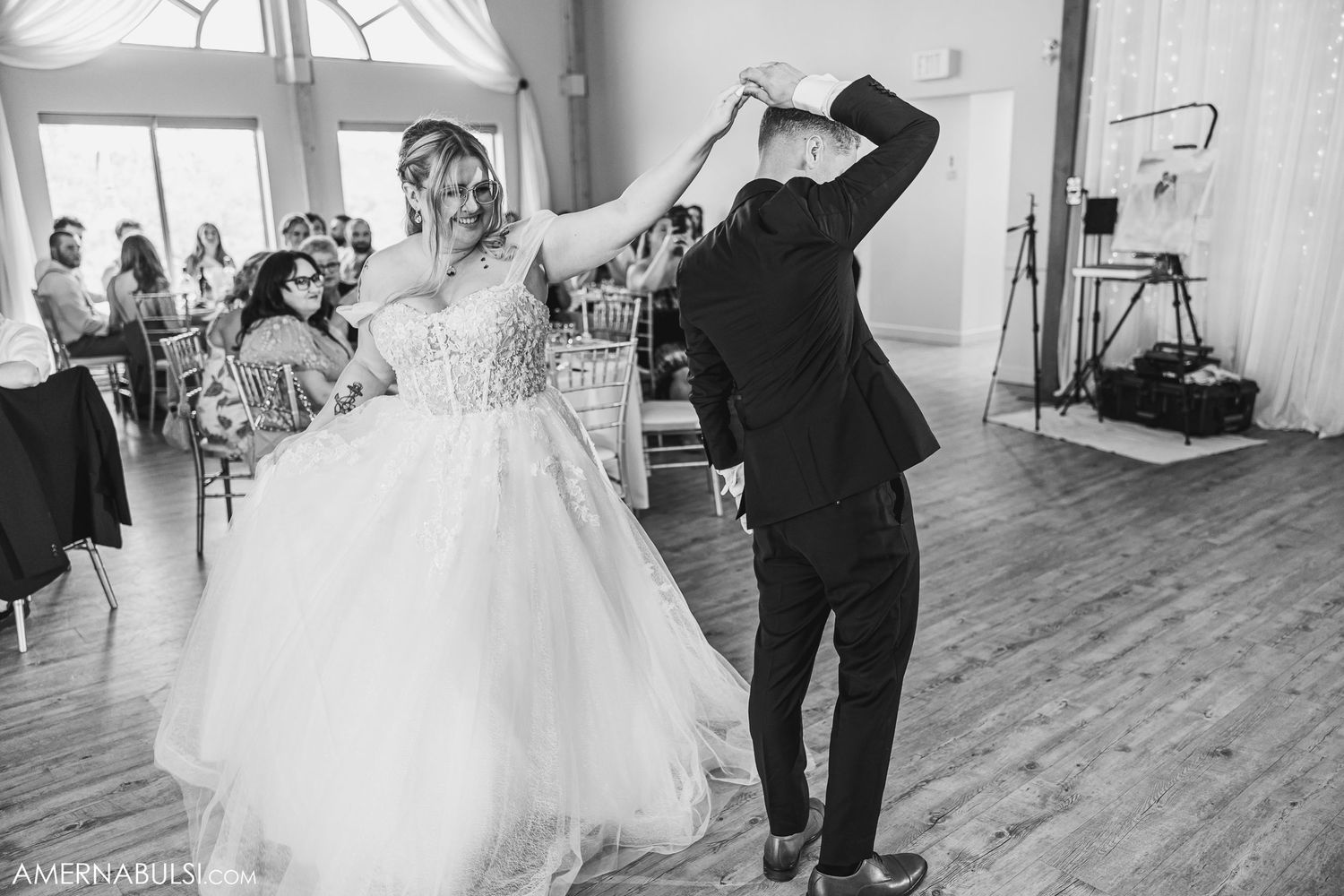 Wedding couple dancing in an elegantly decorated reception space with wooden floors.