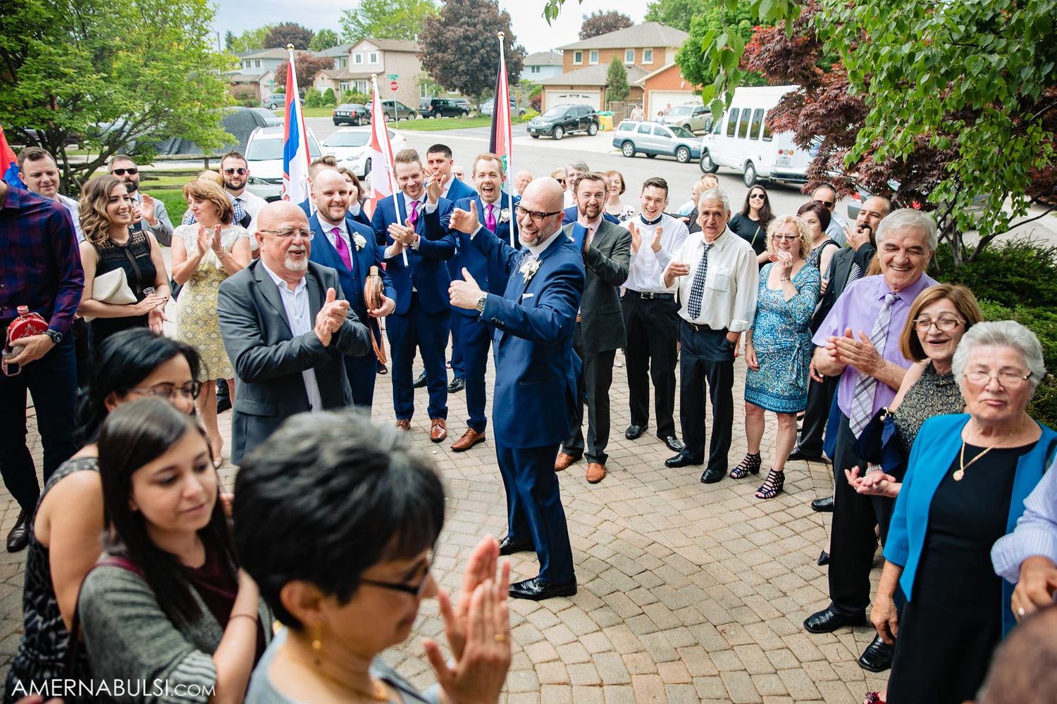 Large group of wedding guests gathered on outdoor brick patio for celebration.