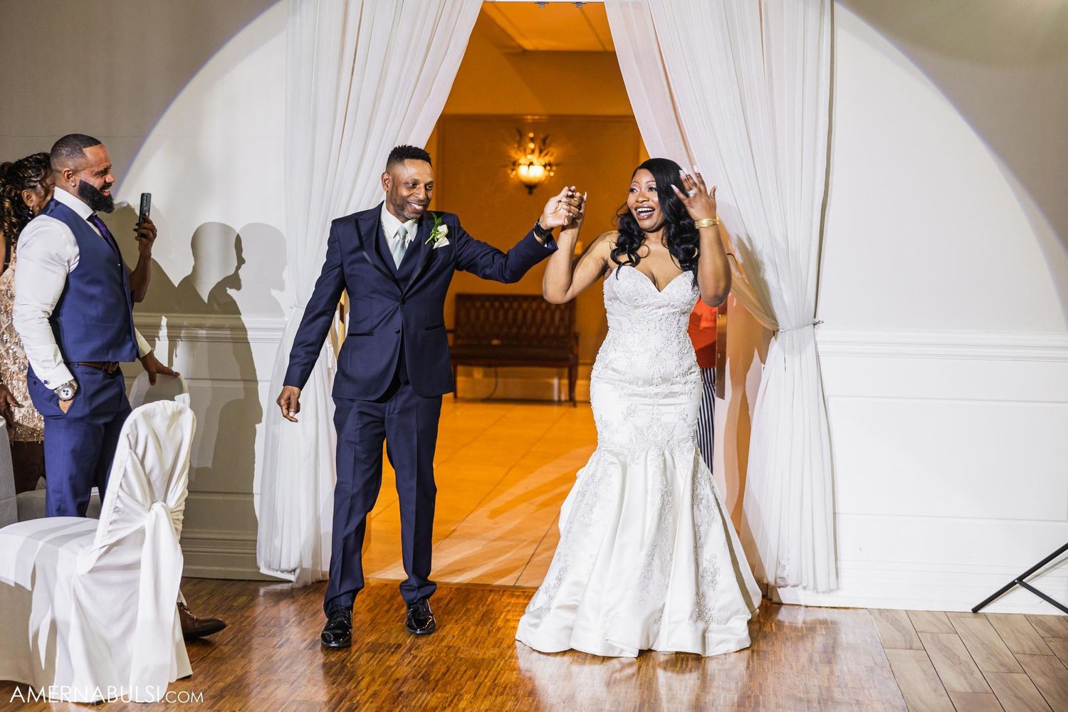 Wedding celebration entrance through white draped archway with couple making grand appearance.