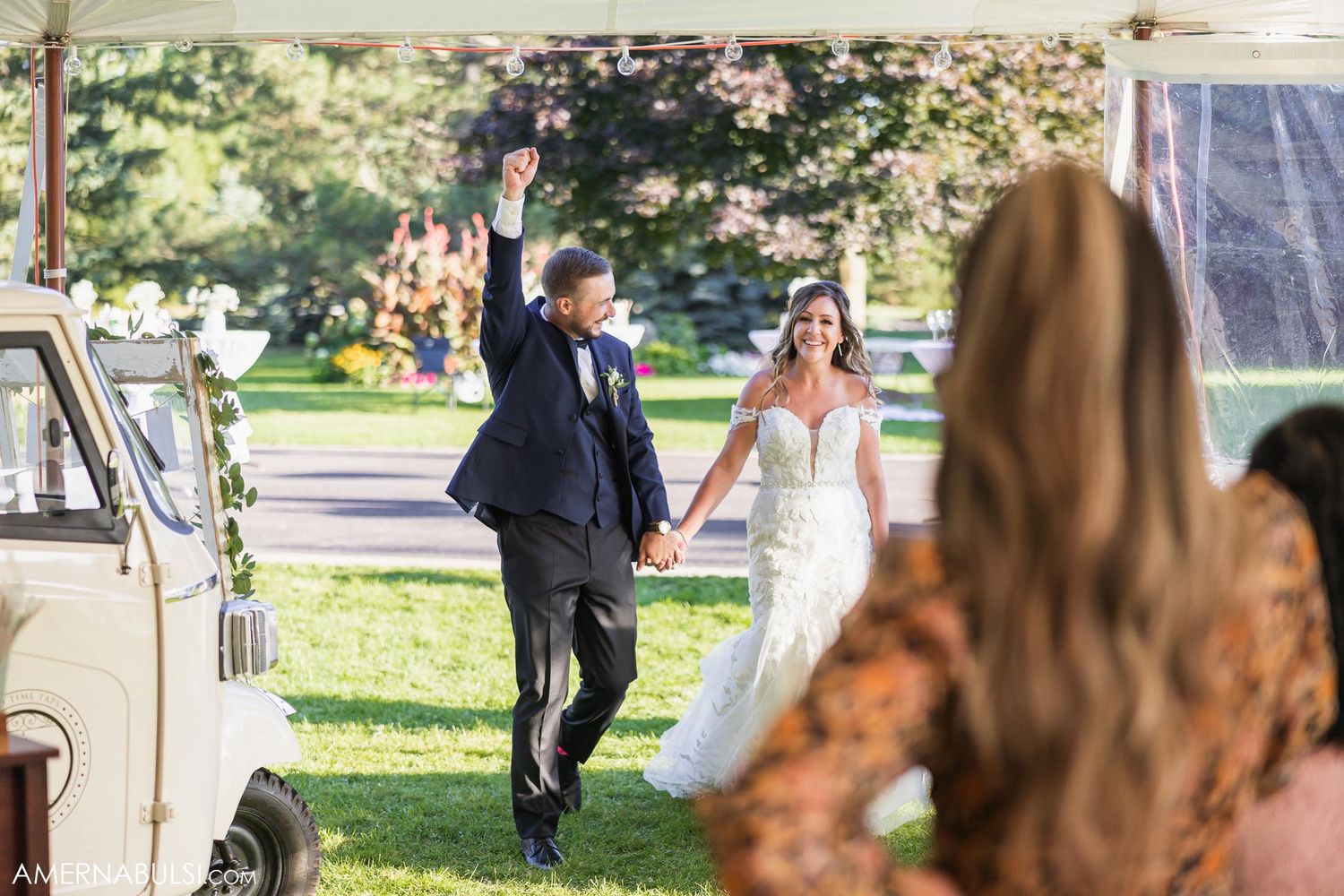 Joyful celebration near vintage van during outdoor wedding reception.