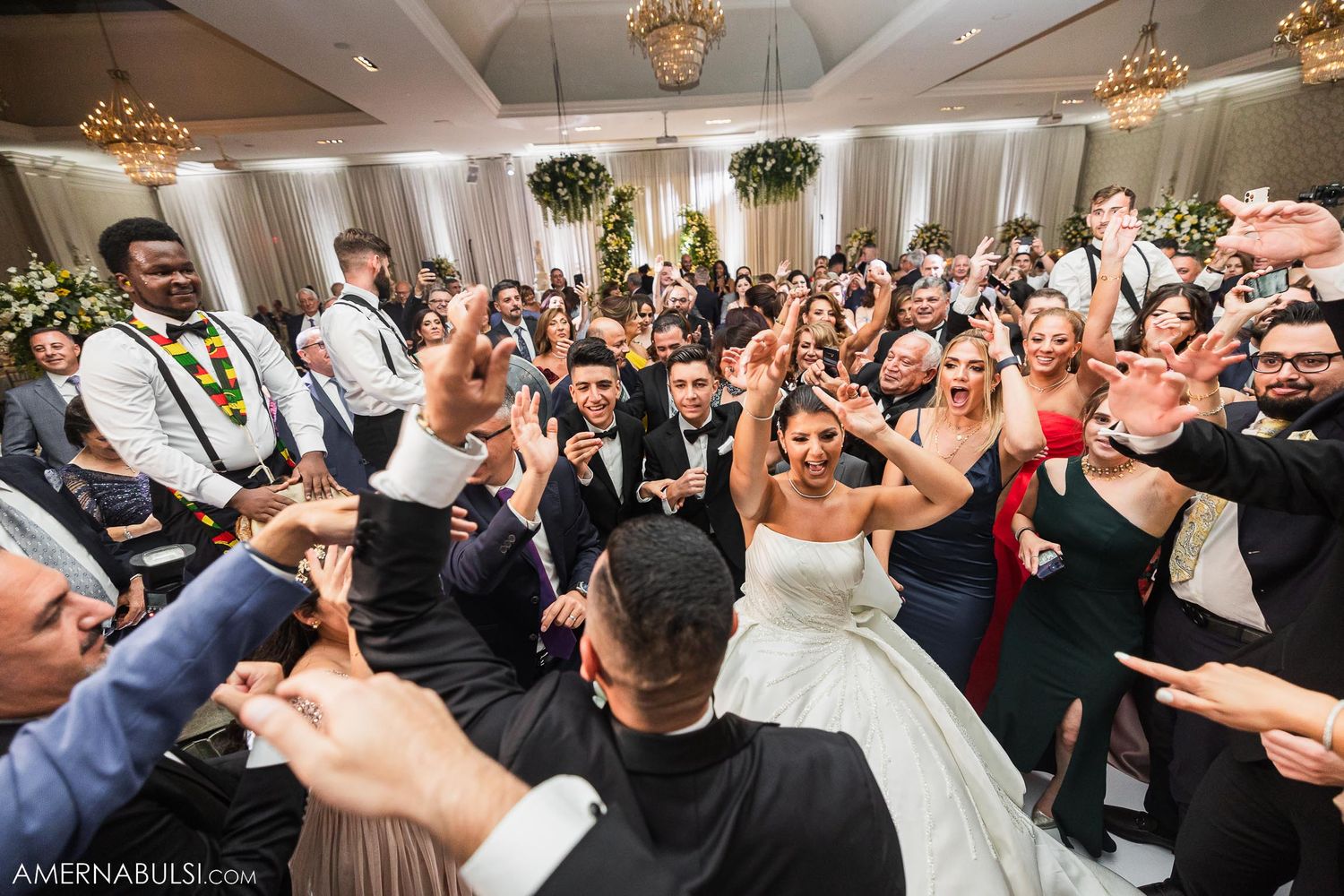 Lively wedding reception with guests dancing and celebrating on a packed dance floor.