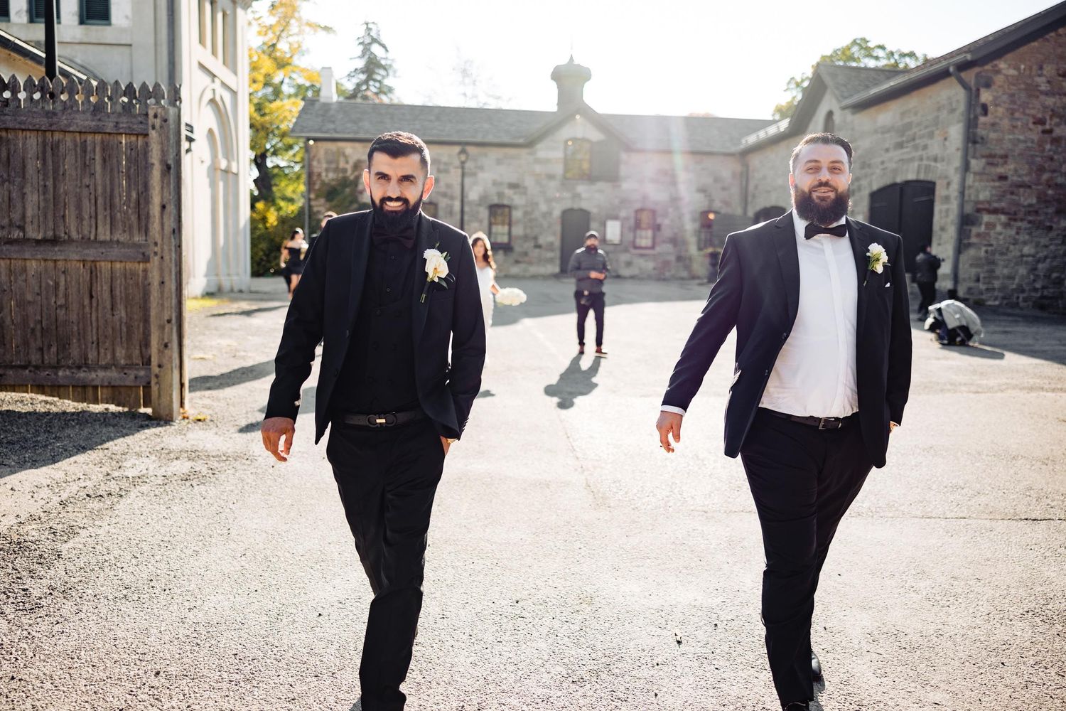 Two friends walking together on sunny street before formal event.