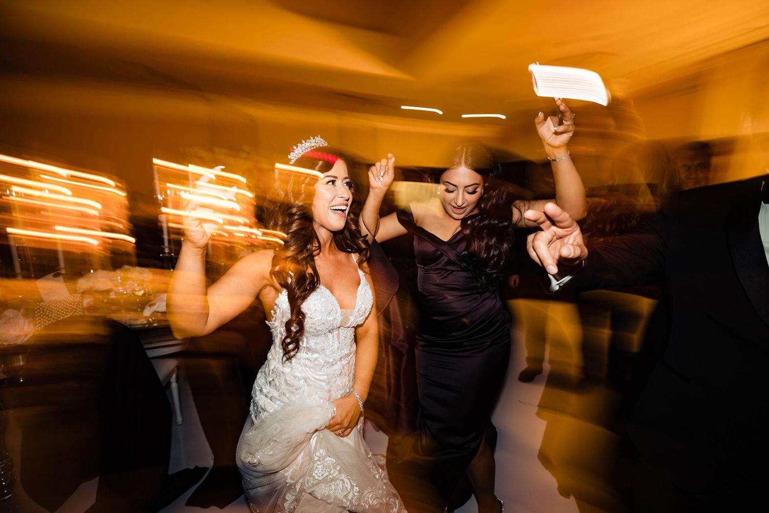 Motion-blurred party scene with dancing silhouettes against warm lighting.