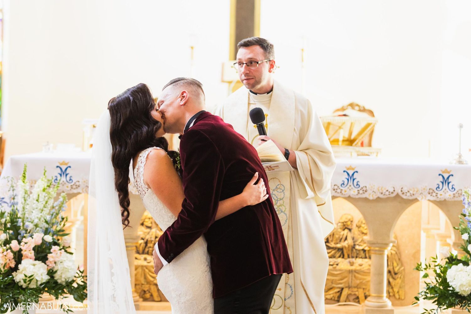 Wedding ceremony moment at ornate church altar with floral arrangements.