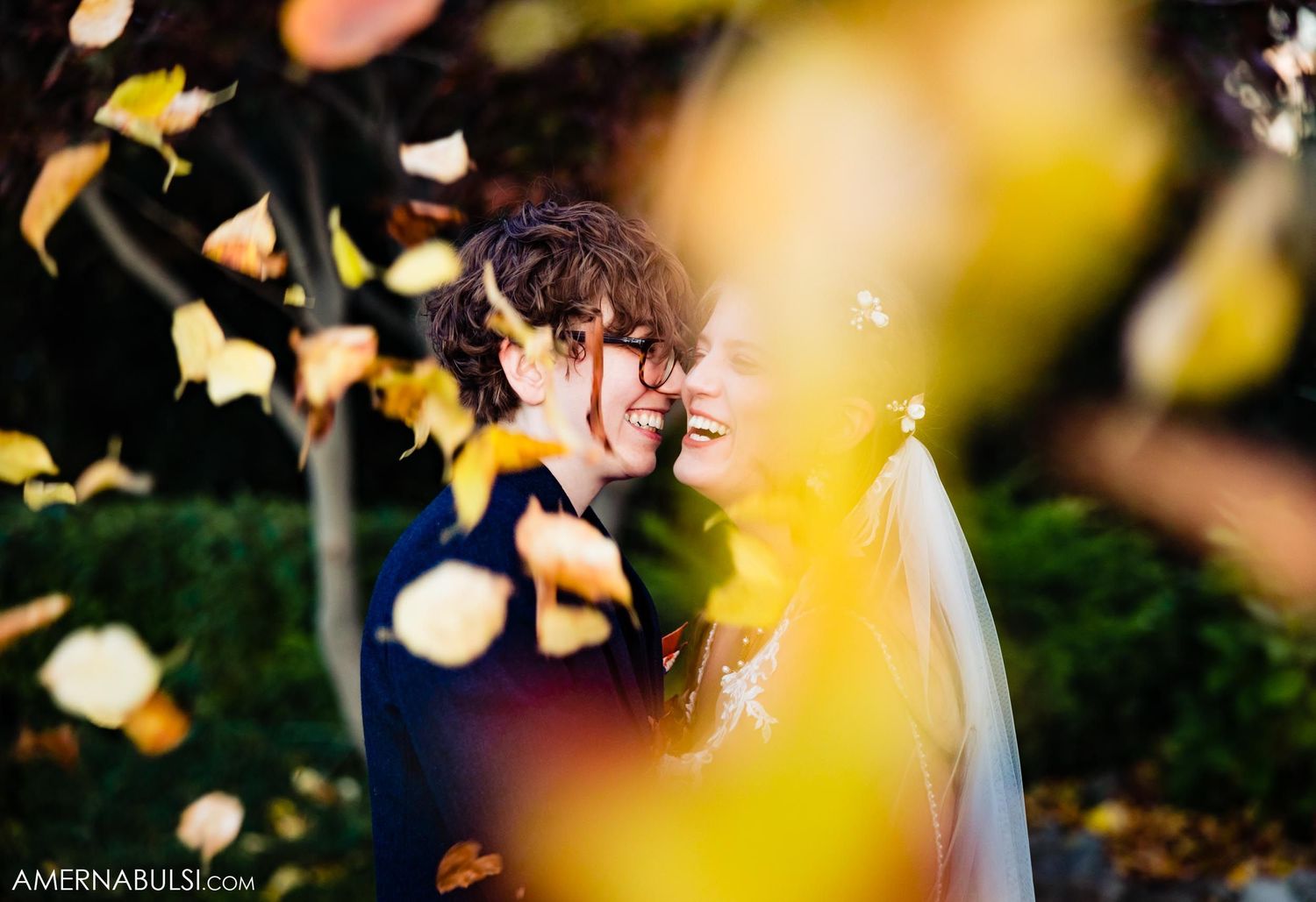 Romantic moment captured through falling autumn leaves at outdoor wedding.