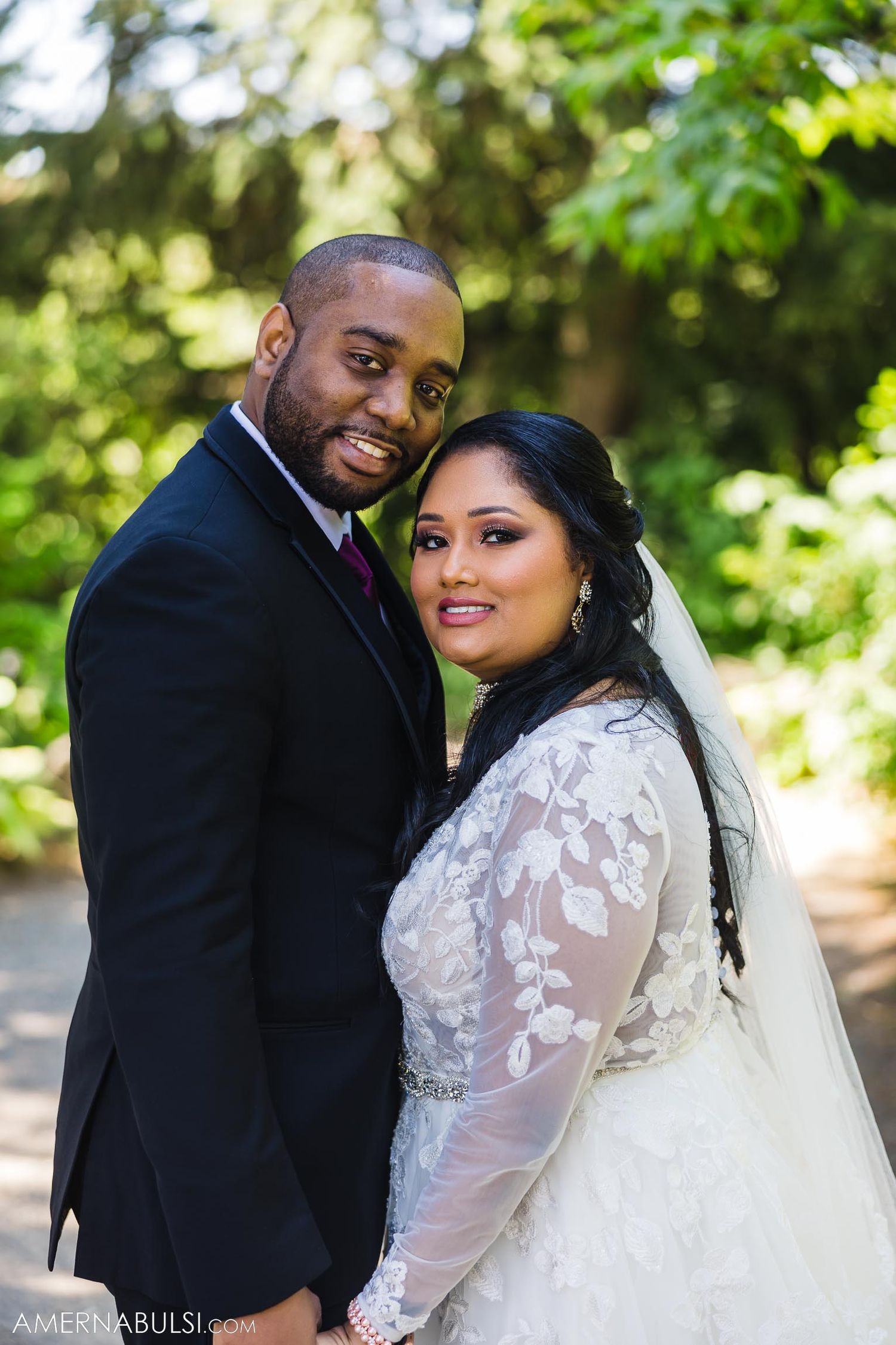 Wedding portrait in a garden setting with couple in elegant white dress and black suit.