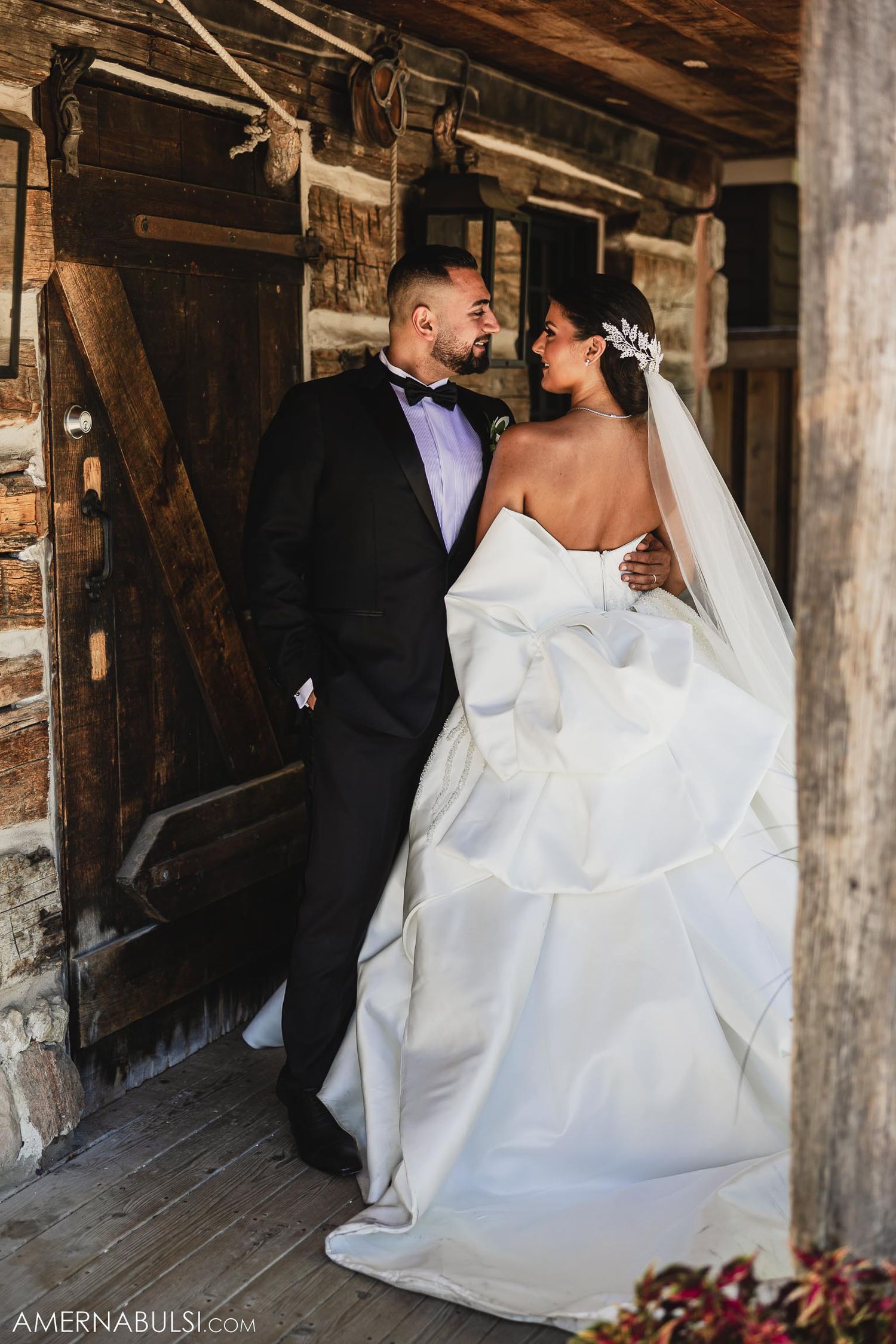 A couple shares an intimate moment in a rustic wooden barn setting on their wedding day.