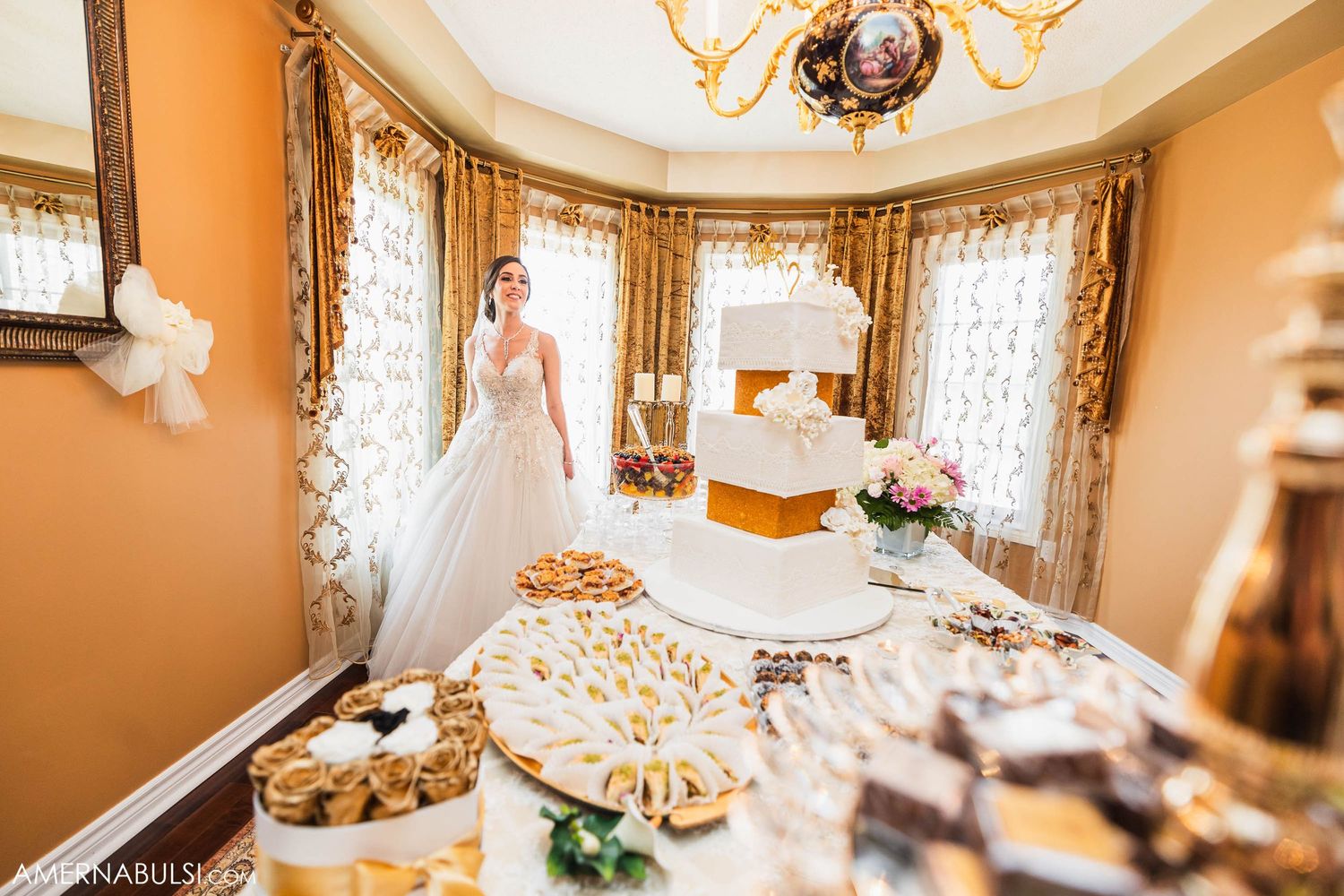 Elegant wedding reception room with dessert table featuring tiered cake and sweets display.
