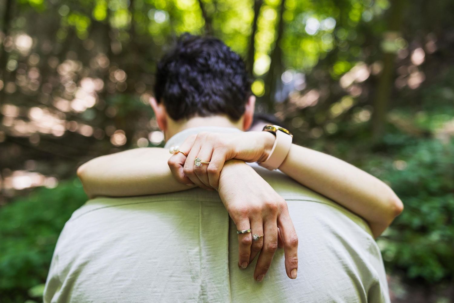 Close-up shot of hands displaying wedding rings against a white shirt.