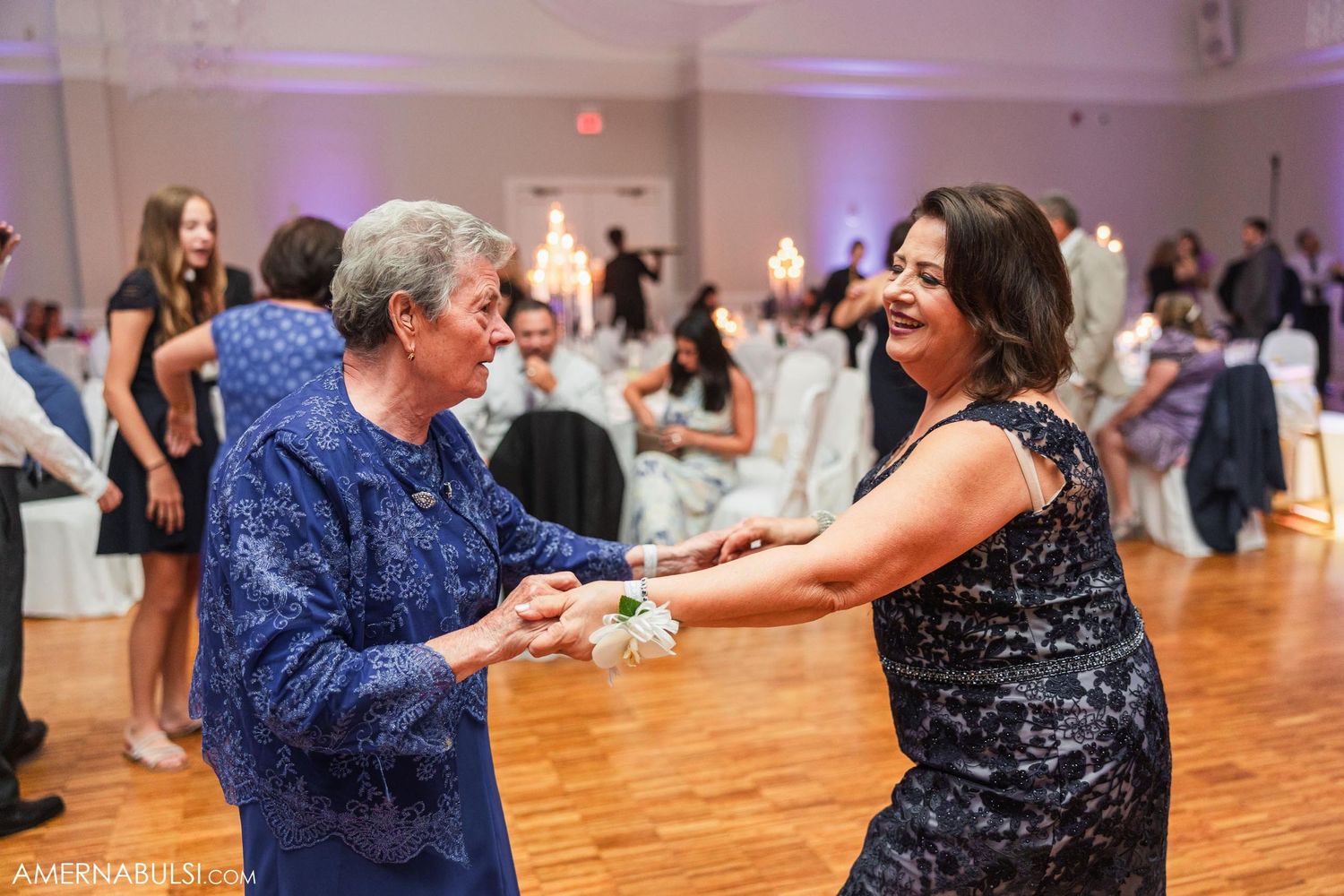 Two guests dancing together on a wooden dance floor at a formal event.