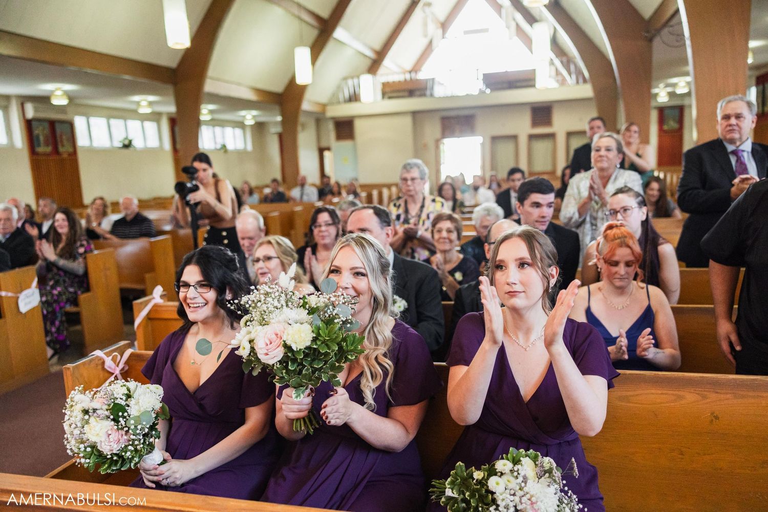 Bridesmaids in purple dresses react emotionally during the wedding ceremony.