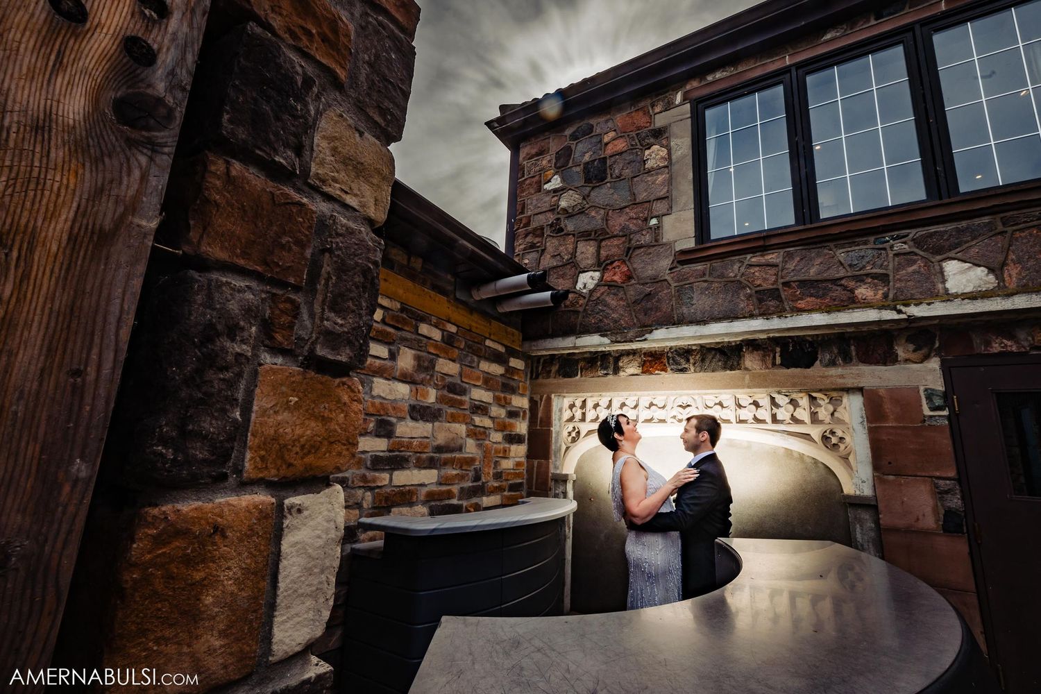 Intimate wedding ceremony moment in rustic stone room with dramatic lighting.