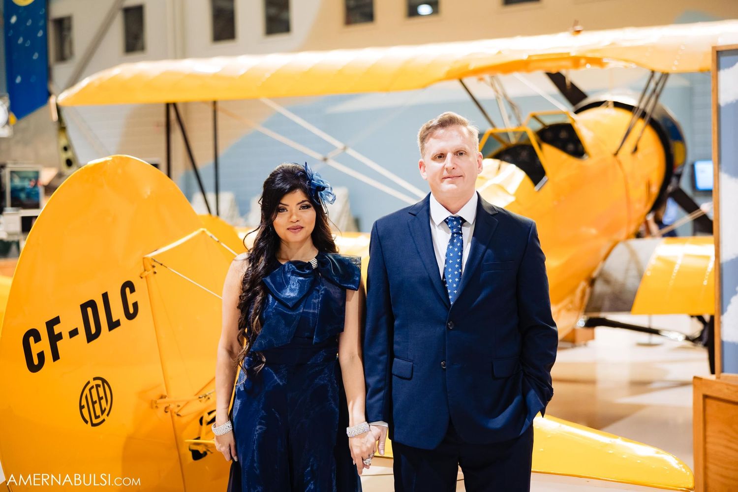 A couple stands near a yellow vintage aircraft marked CF-DLC.