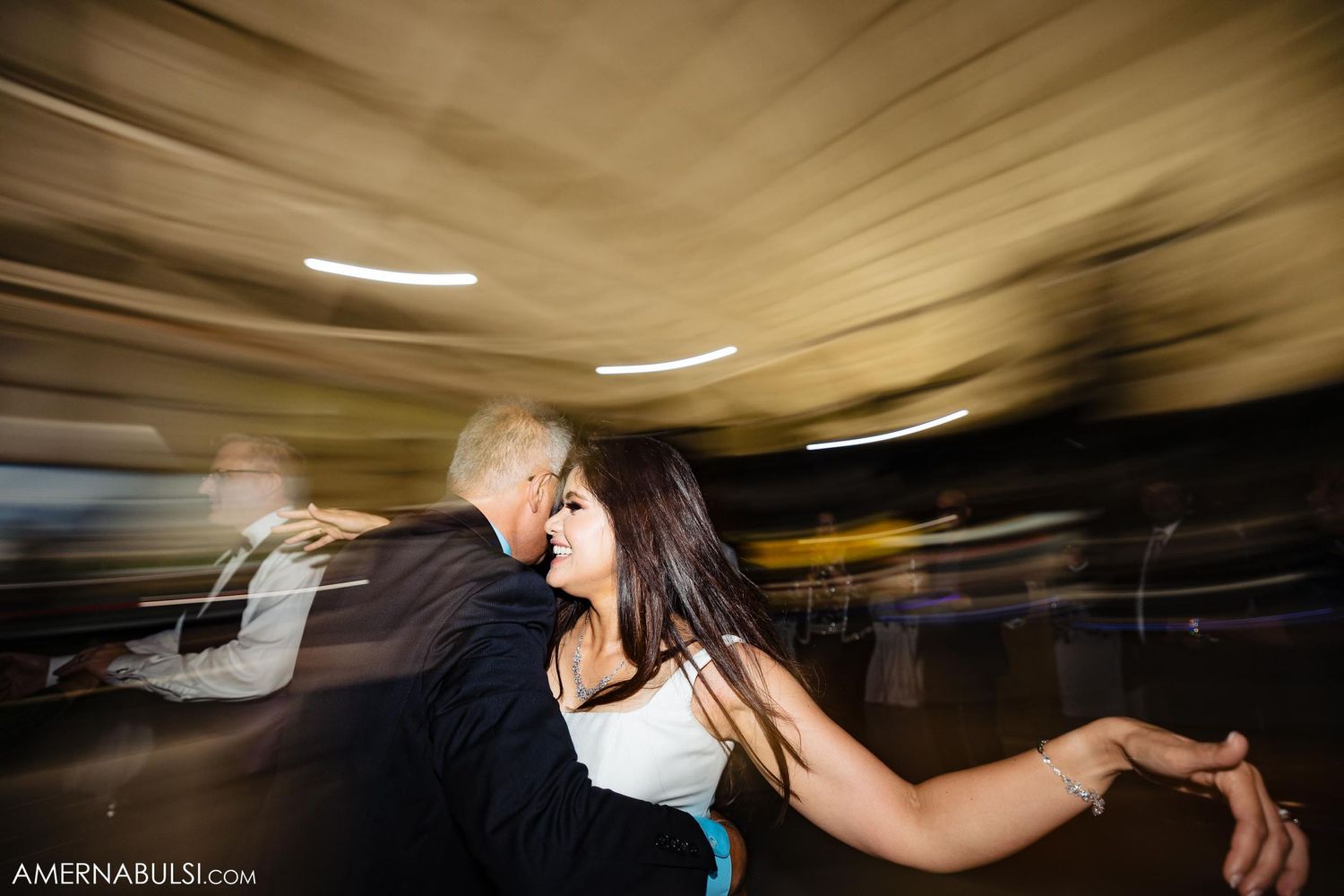 Dynamic shot of dancing couple at wedding reception with swirling motion blur effects.