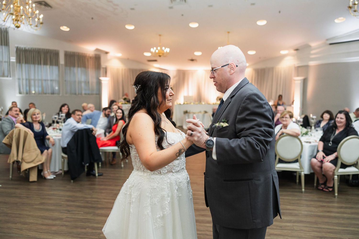 A wedding dance at an indoor reception venue with decorative lighting.