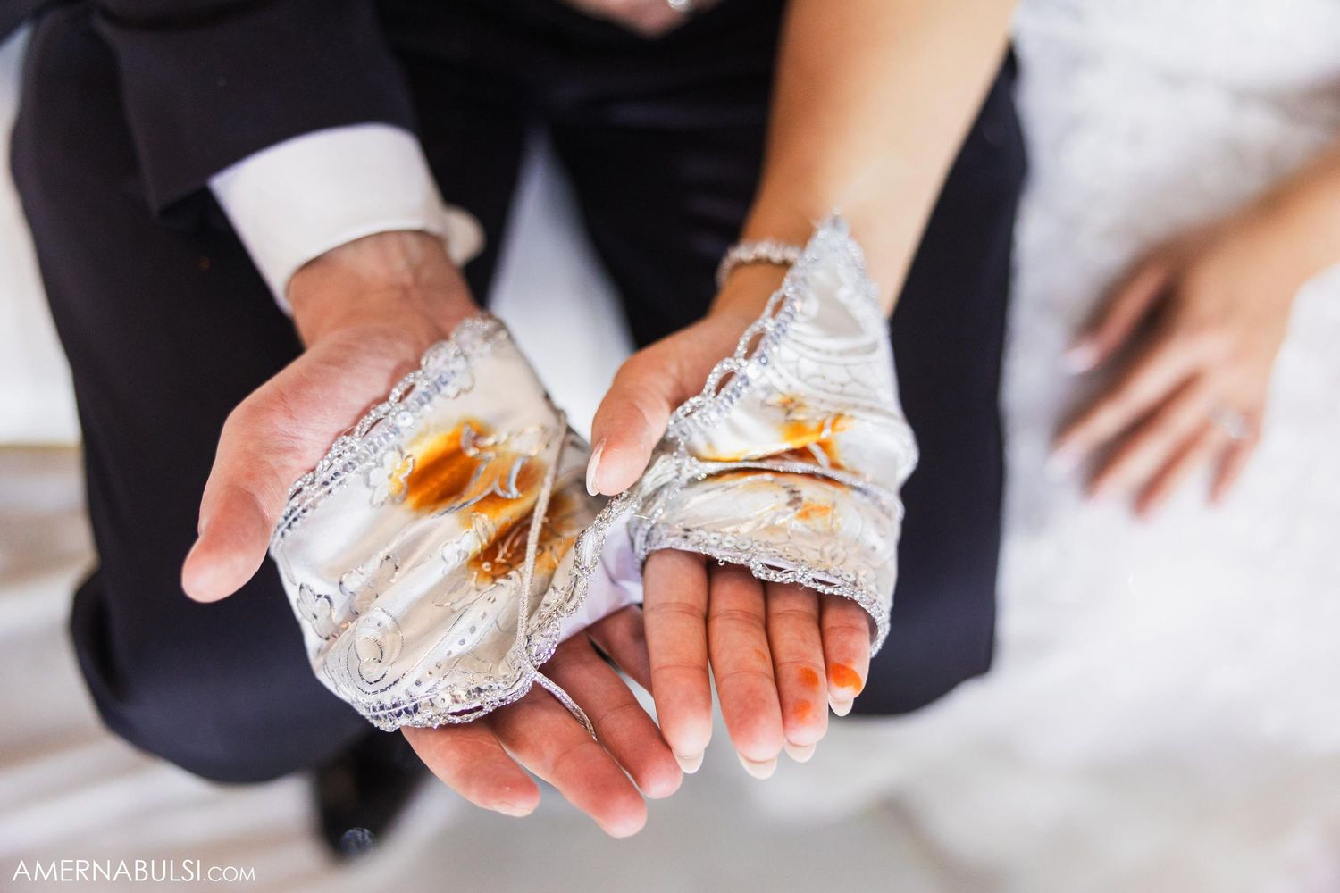 Close-up of wrapped sandwiches held in formal wedding attire.