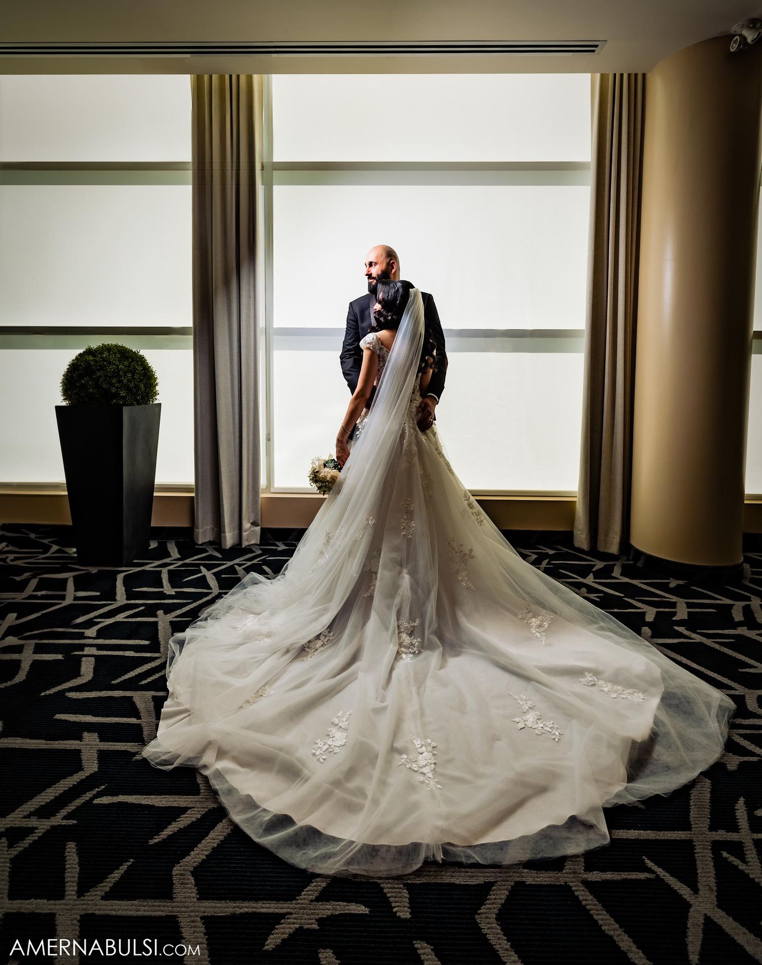 Stunning wedding gown with long train displayed in elegant hotel setting.