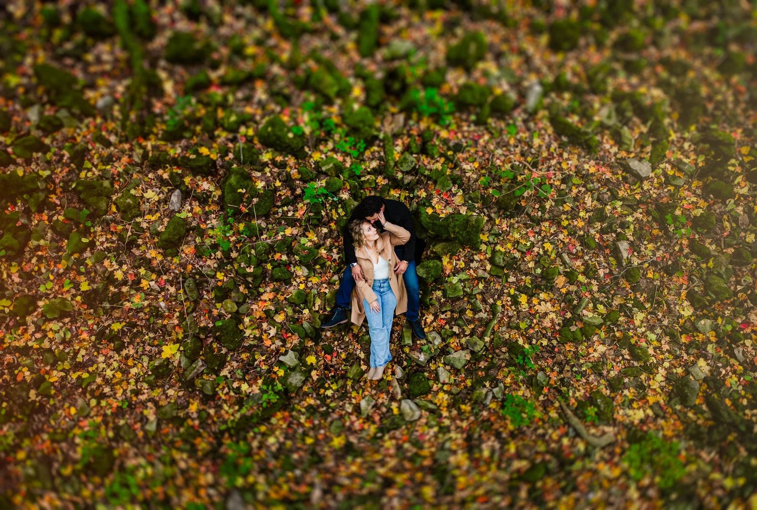 Drone shot of couple surrounded by blooming flowers in spring meadow.