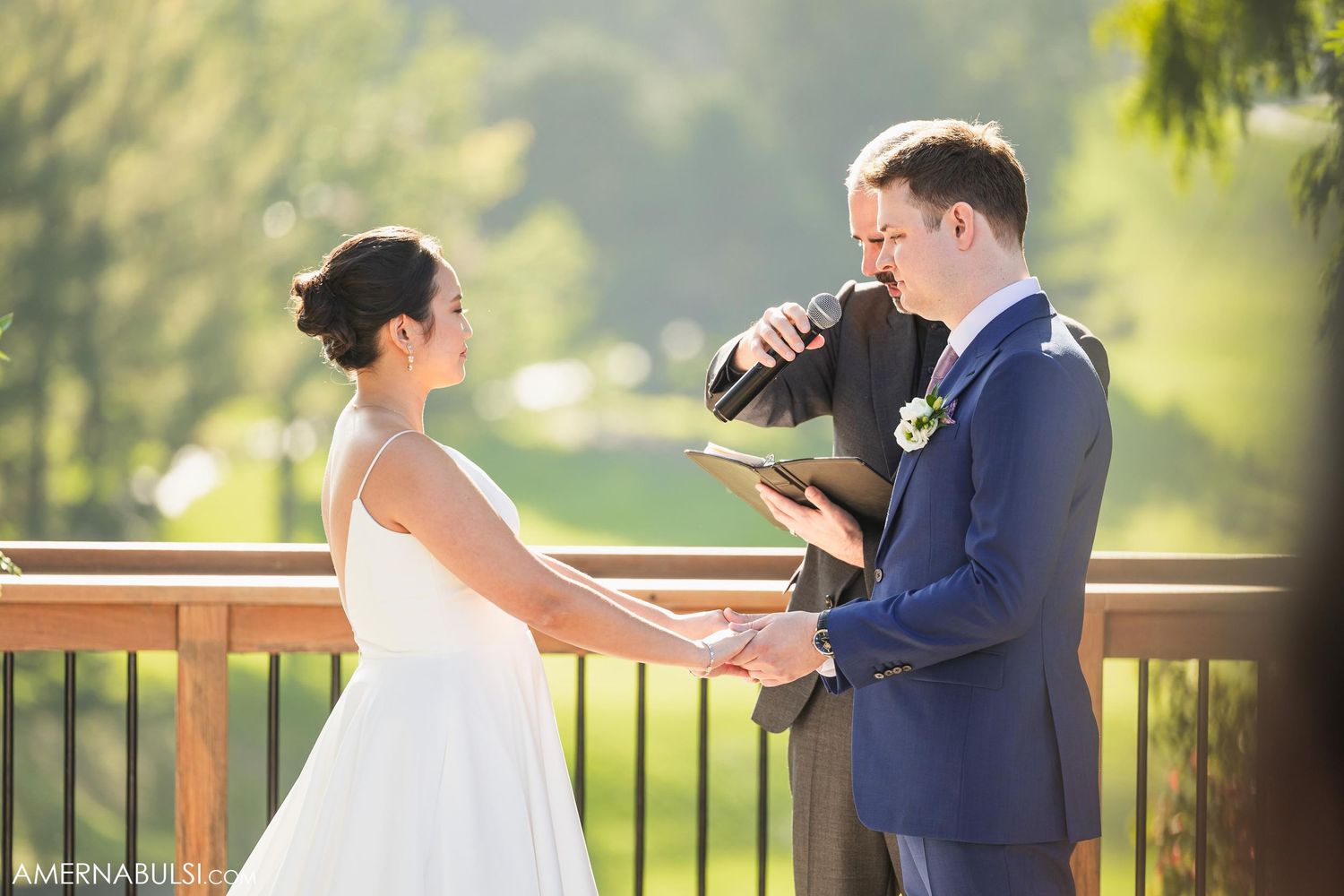 Couple exchanging rings during outdoor wedding ceremony.