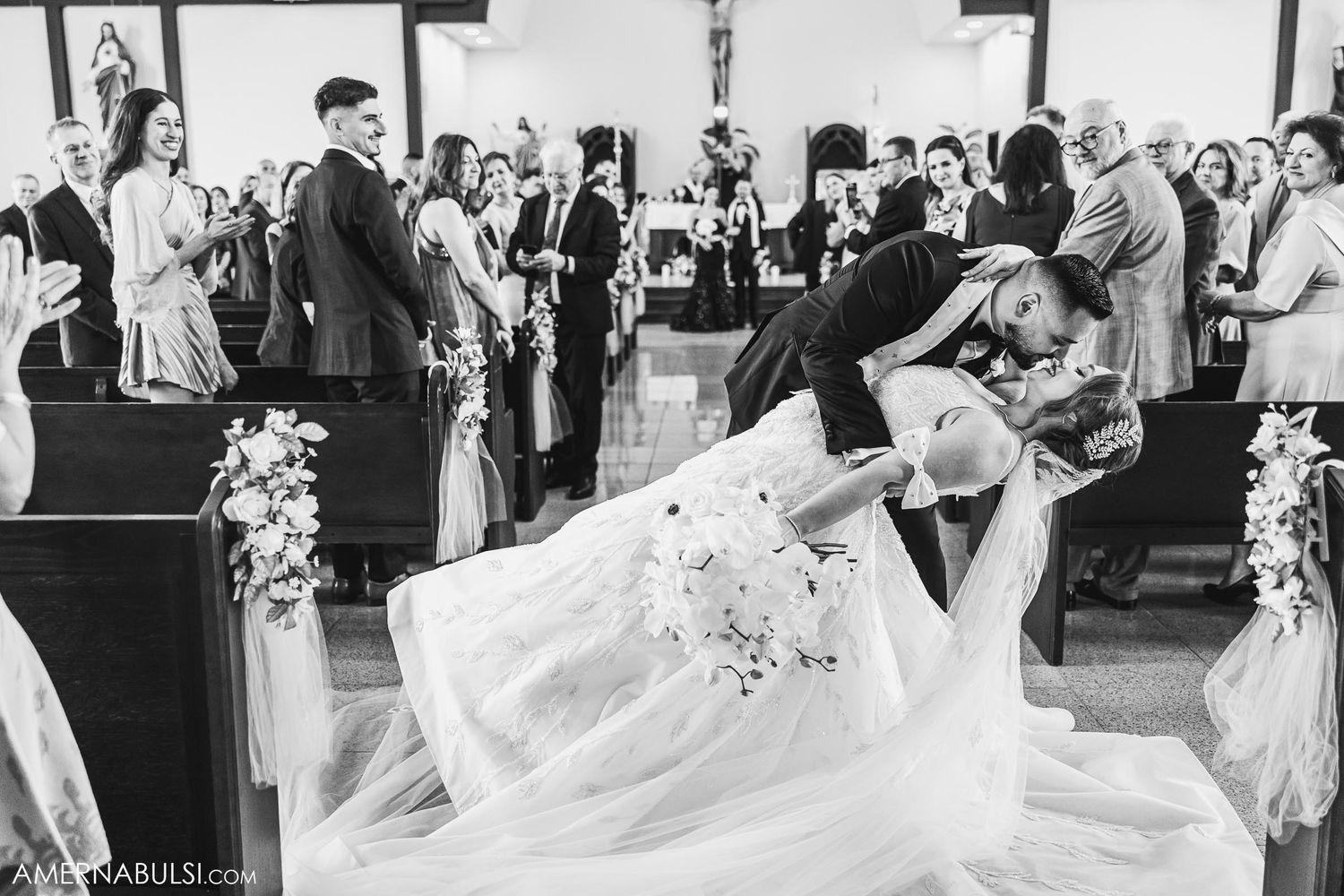 A dramatic dip during a first dance at a wedding ceremony in a church with elegant floral decorations.