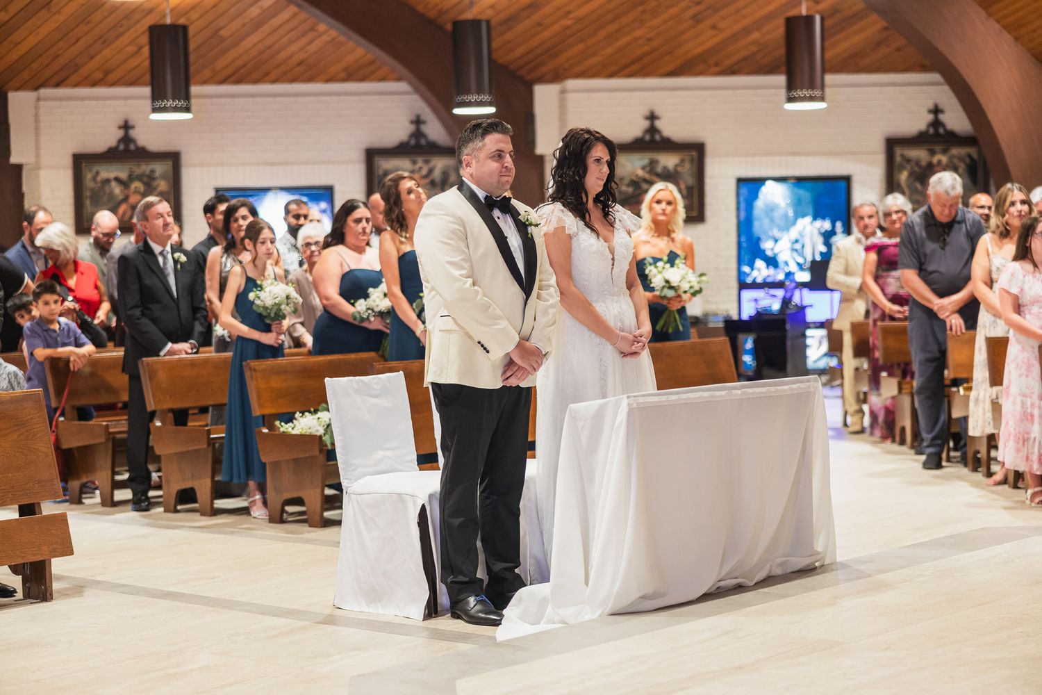 Bride and groom stand at the altar during a traditional church wedding ceremony with guests seated.