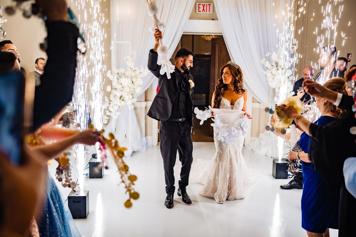 Wedding celebration with indoor sparklers and white drapery creating a magical entrance.