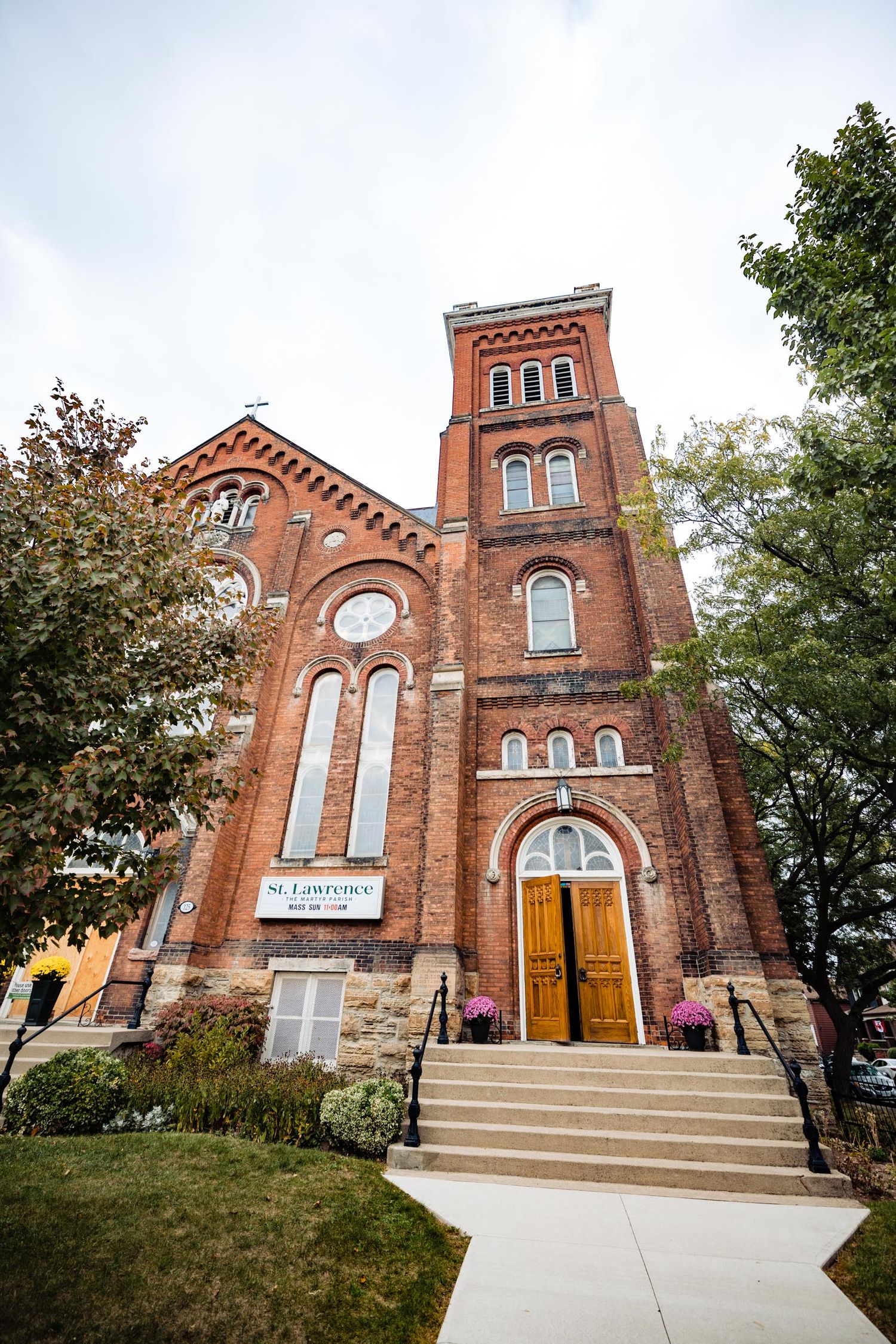 Exterior view of historic red brick church with tall tower and arched windows.