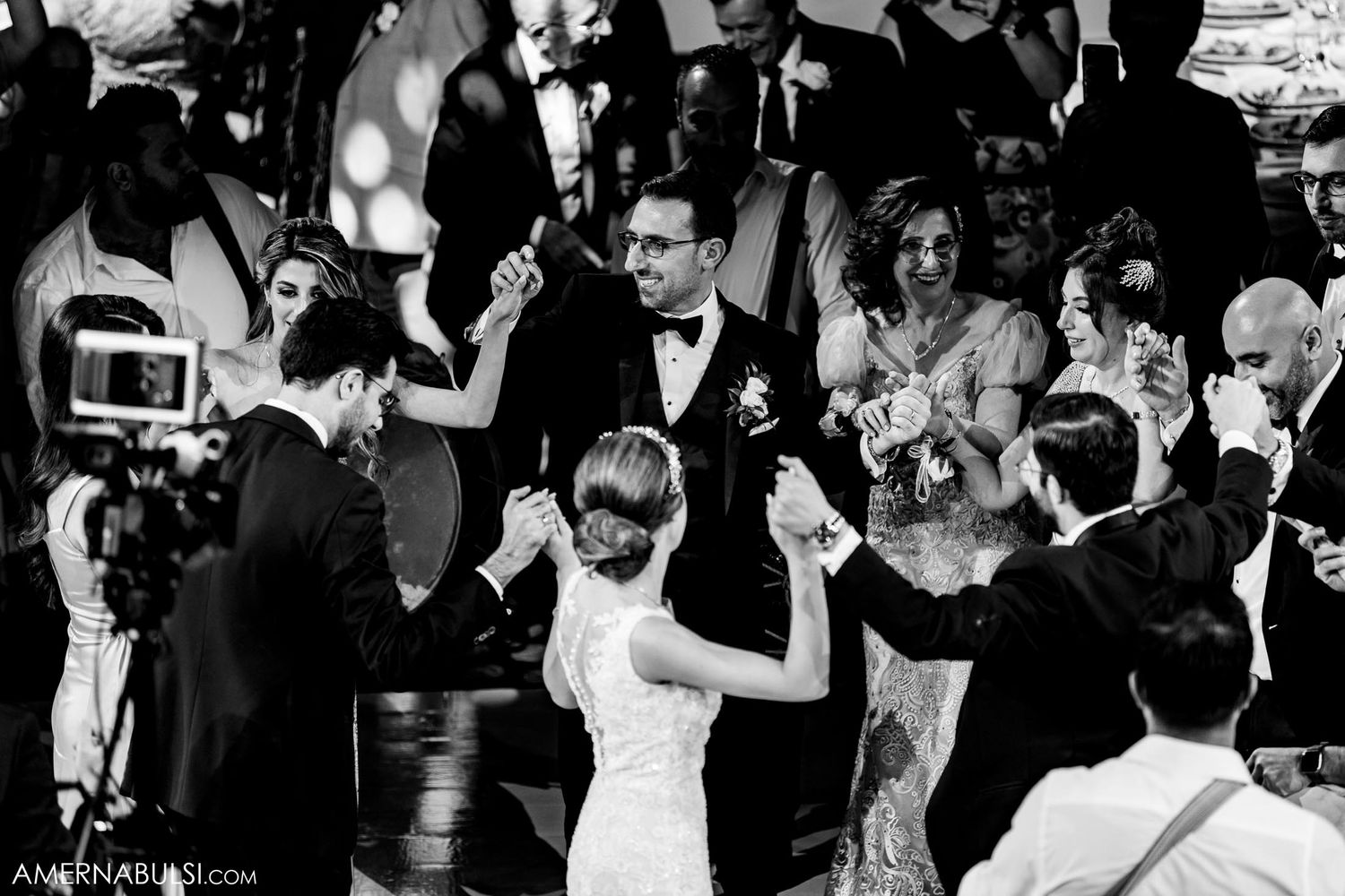 Wedding guests dancing and celebrating on a lively dance floor in black and white photography.