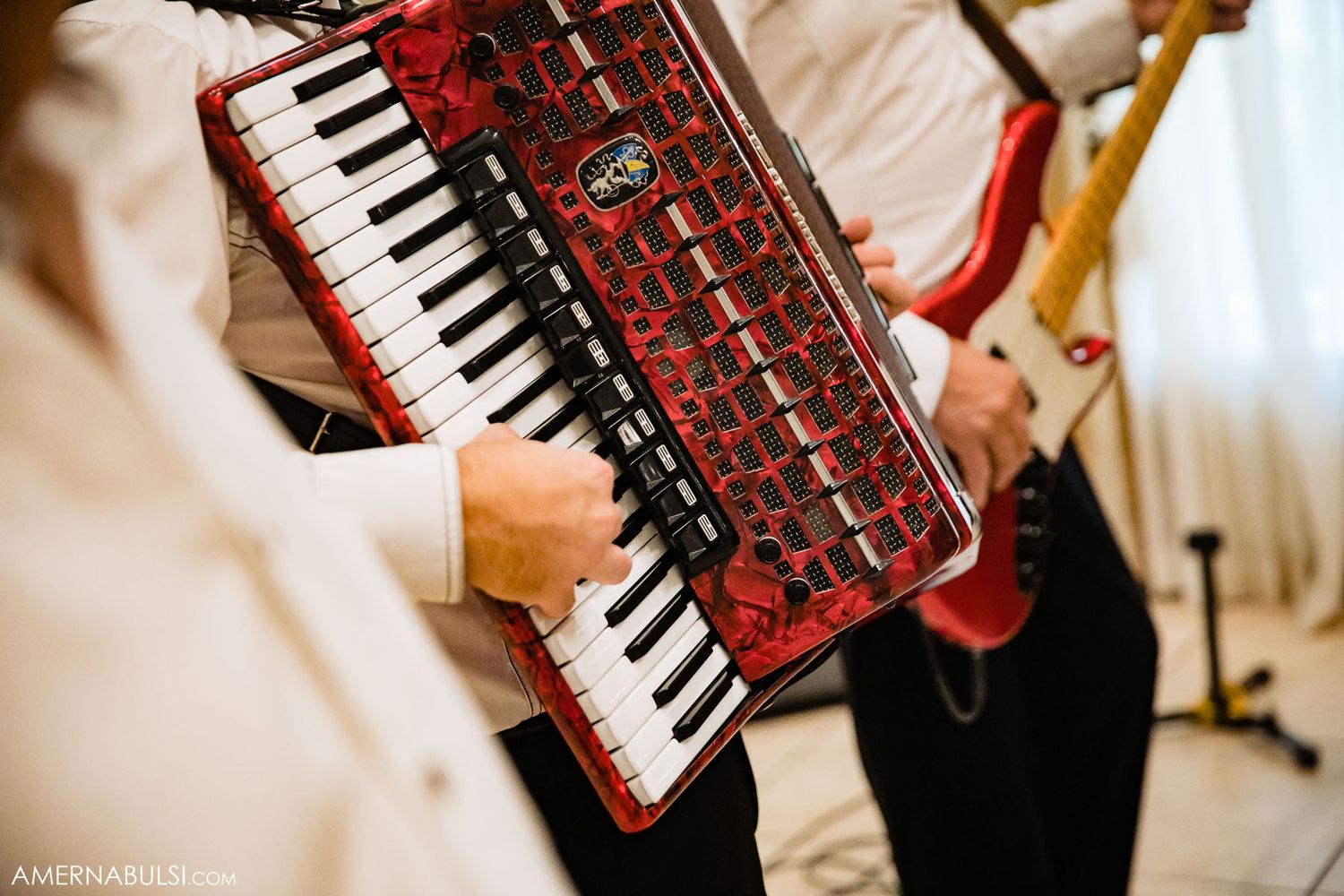 Close-up shots of red and black accordion being played at a wedding celebration.