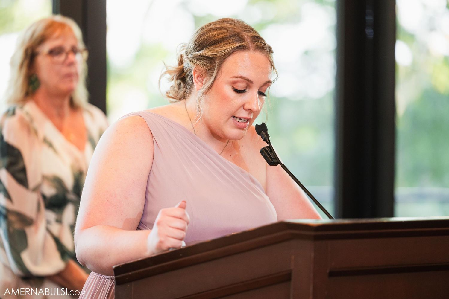 A wedding guest delivers a speech at a wooden podium during the reception.