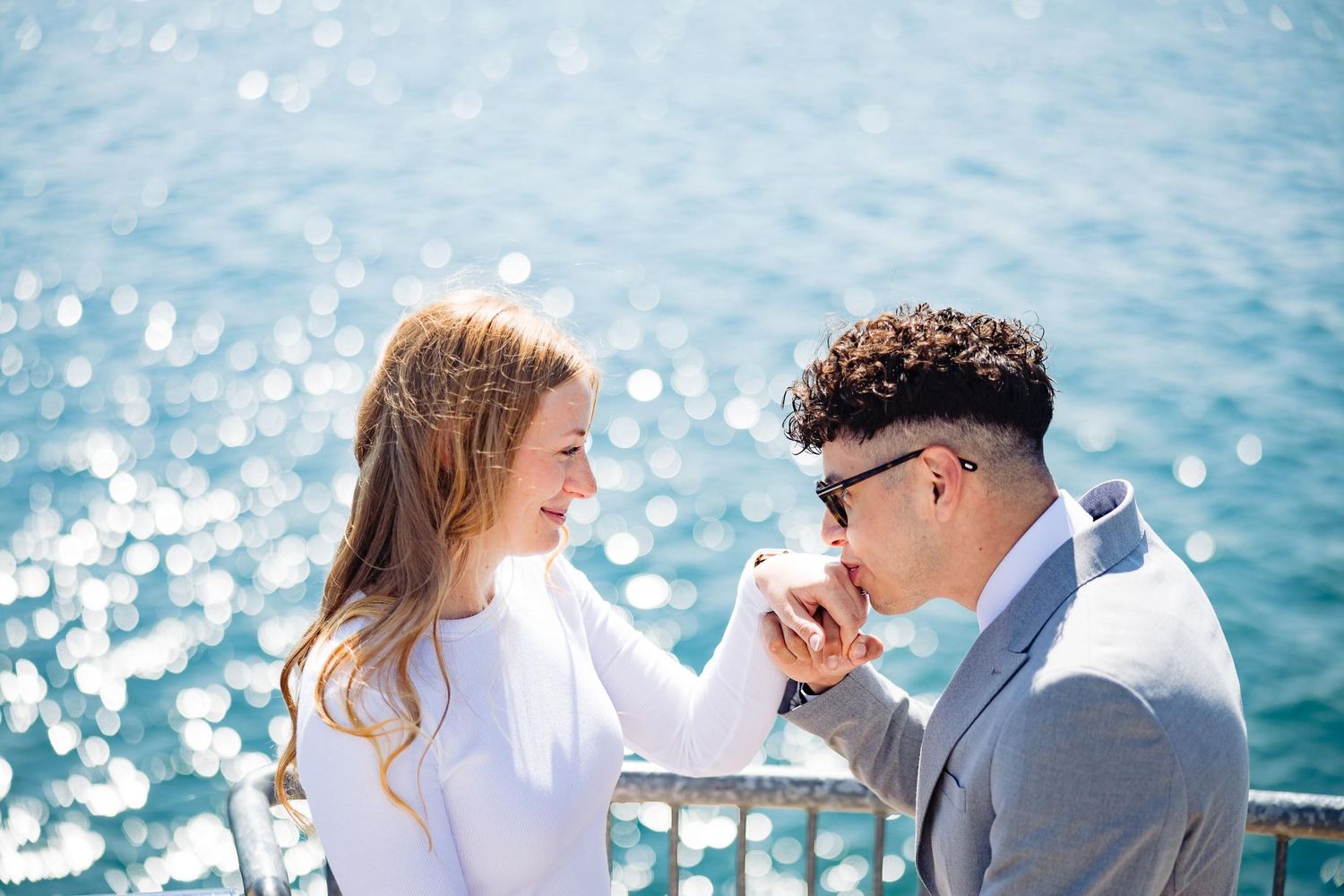 Romantic moment between couple on boat deck with sunlit ocean backdrop.