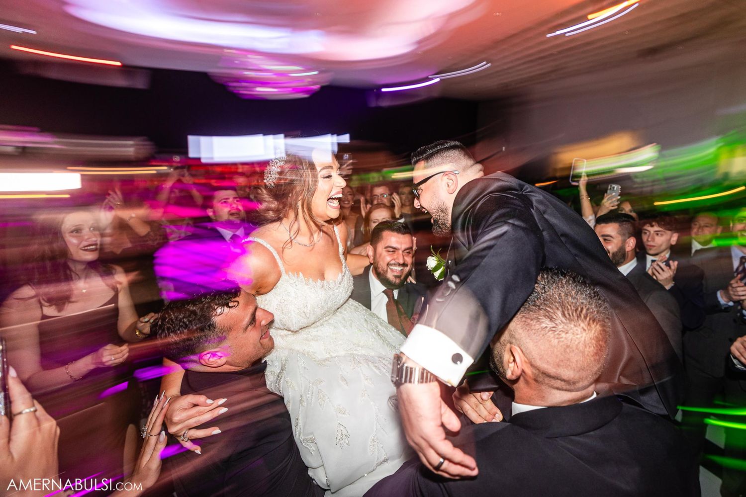 Energetic dancing captured with motion blur under colorful reception venue lighting.