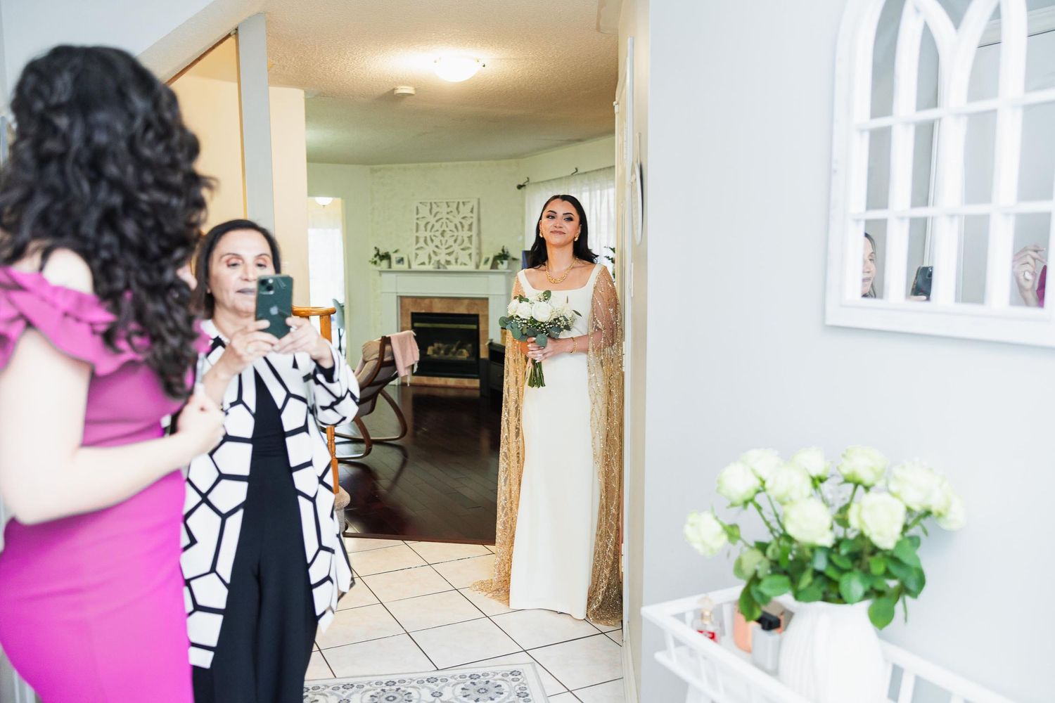 A bride in a white dress makes an entrance while others react with excitement.