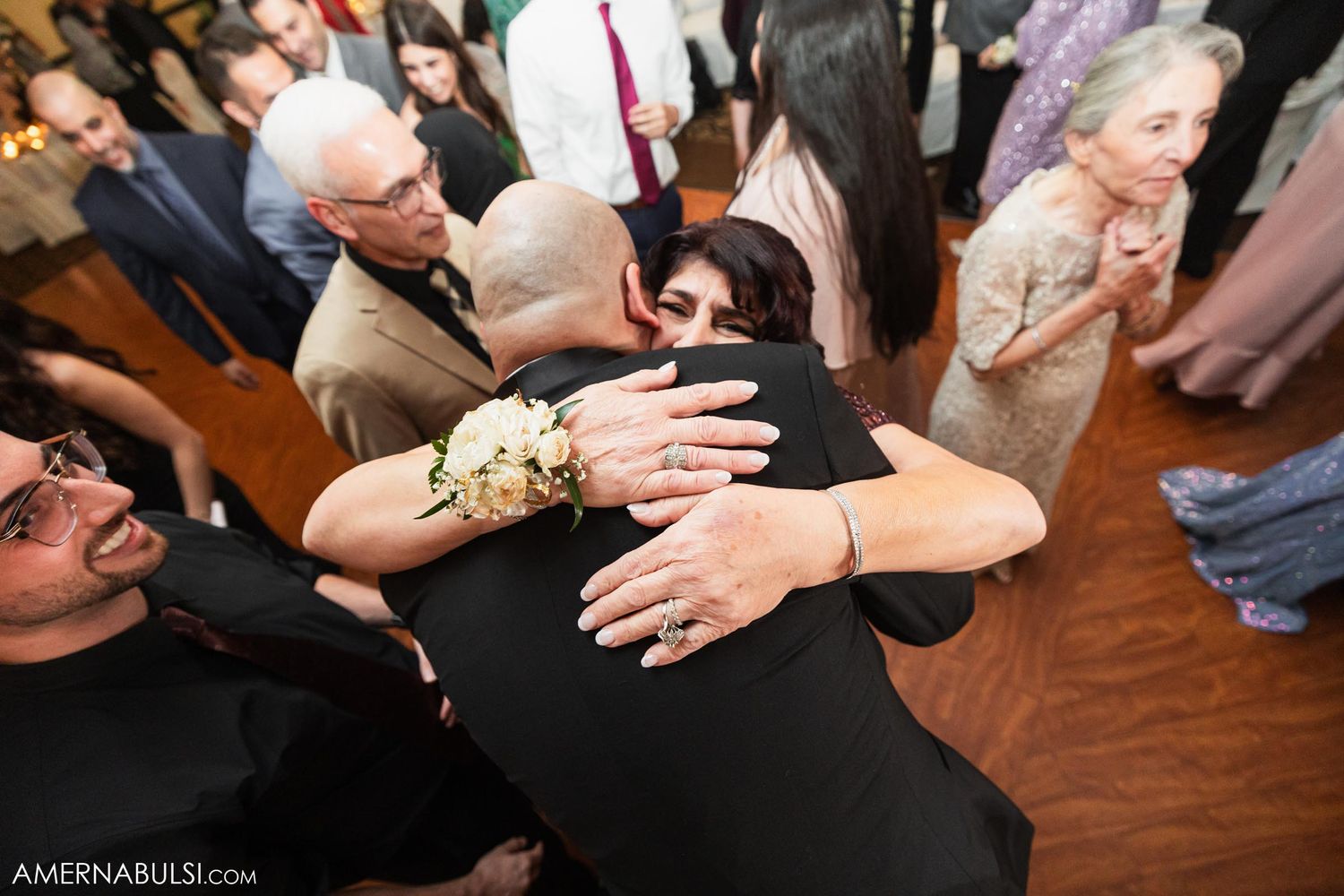 Emotional embrace shared between wedding guests during reception celebration.