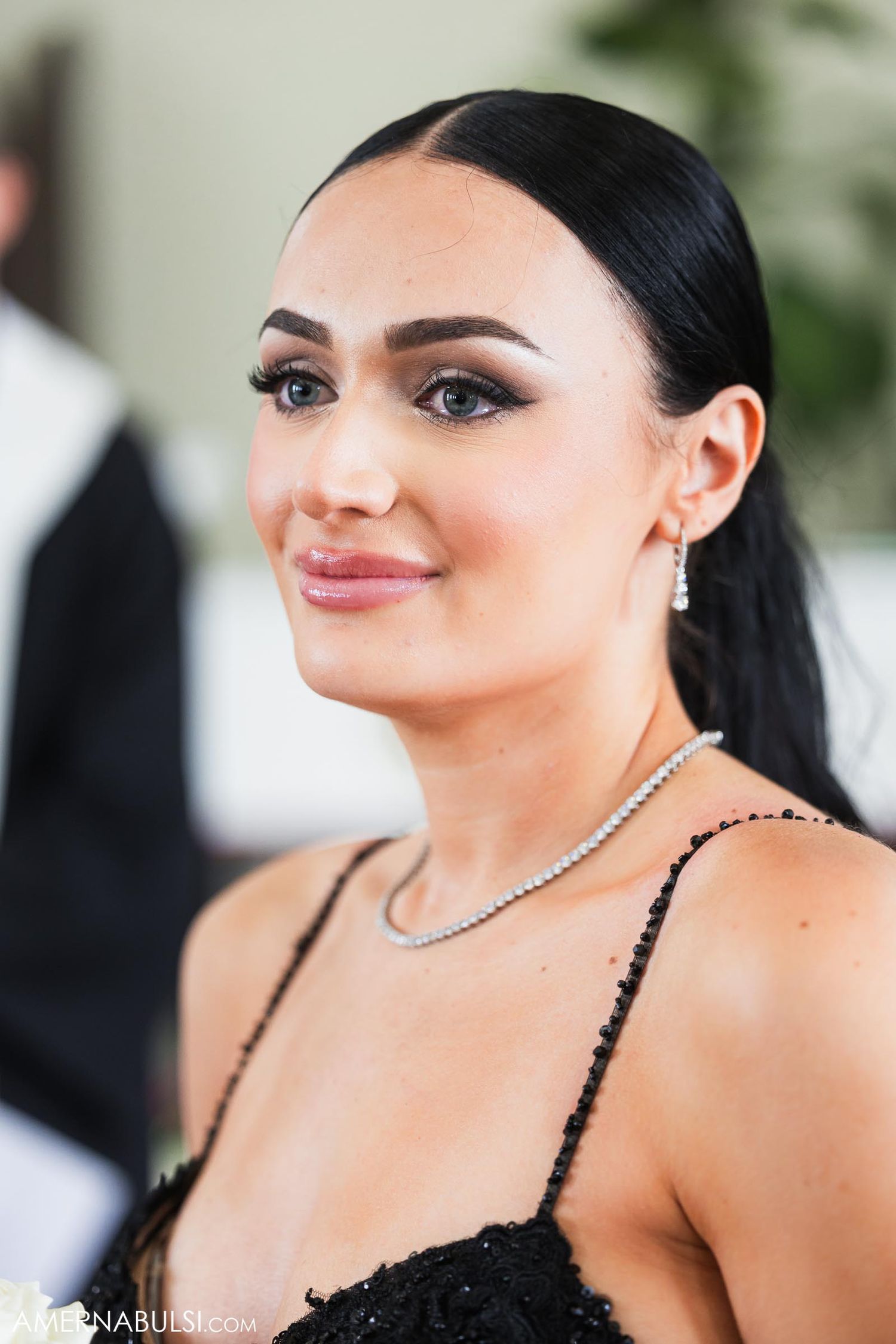 Close-up portrait of wedding guest wearing black dress and diamond necklace.