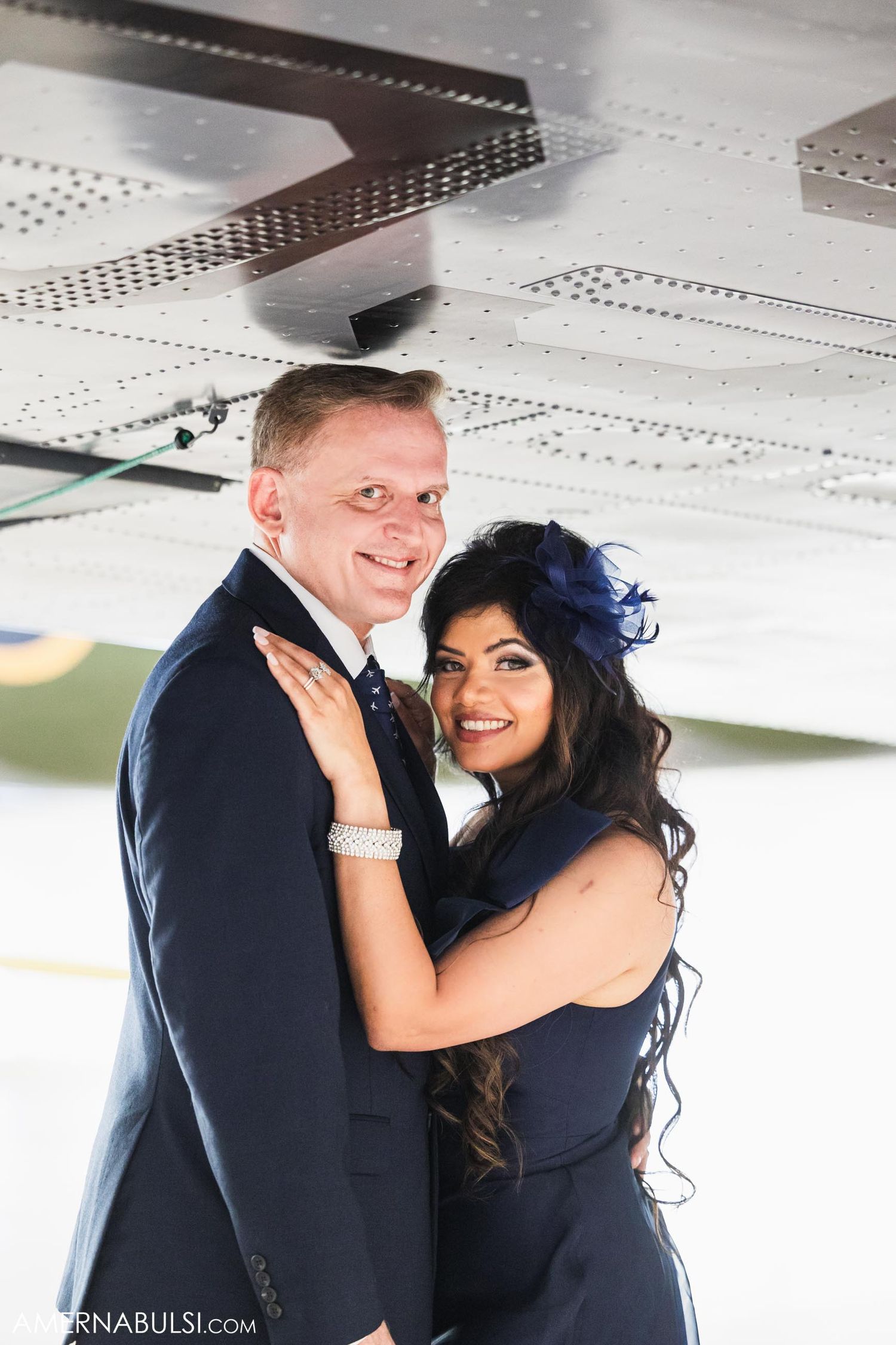 Joyful moment captured under aircraft wing during engagement photoshoot.