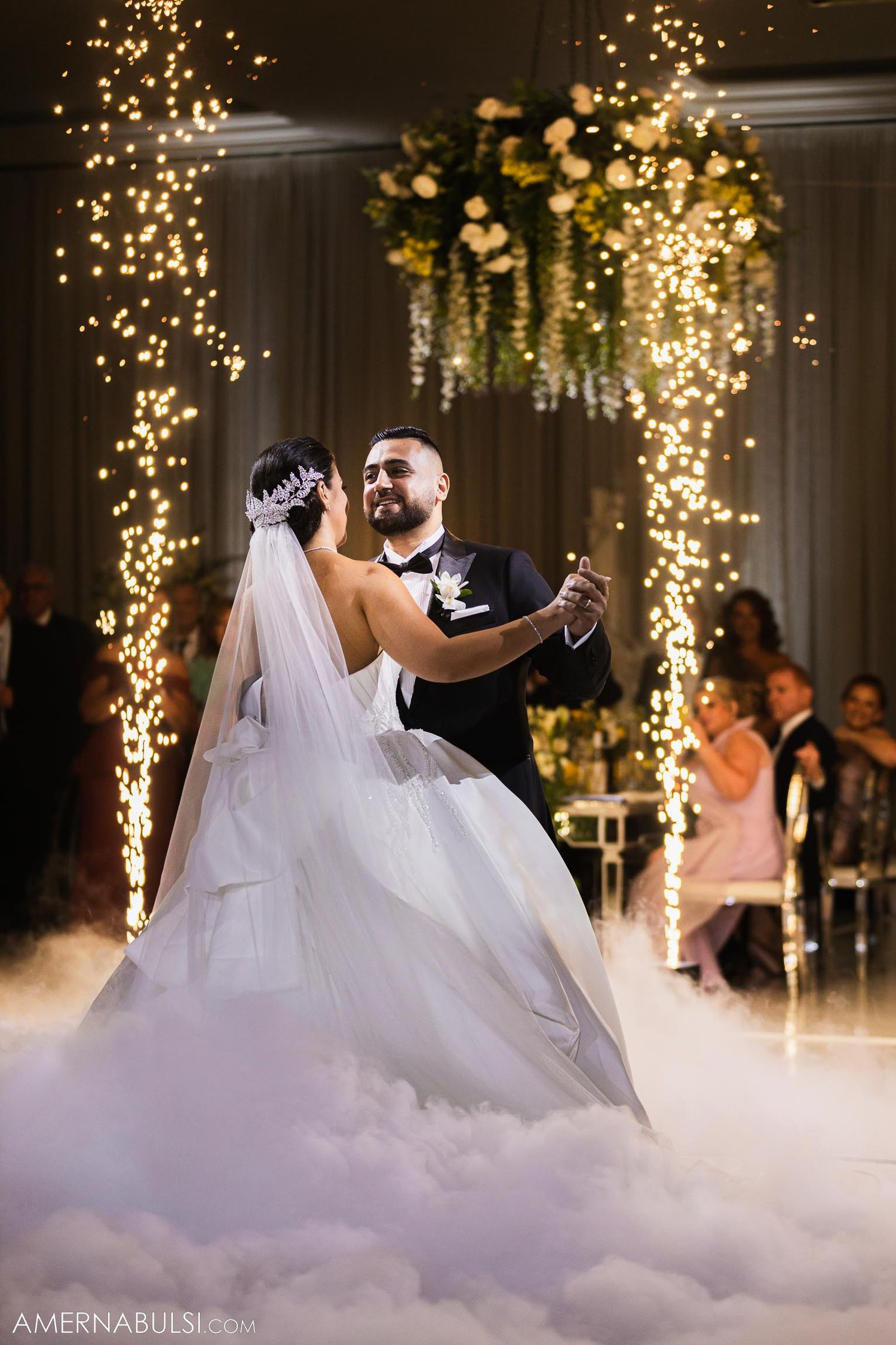Bride and groom dance surrounded by sparklers and low-lying fog effects at reception.