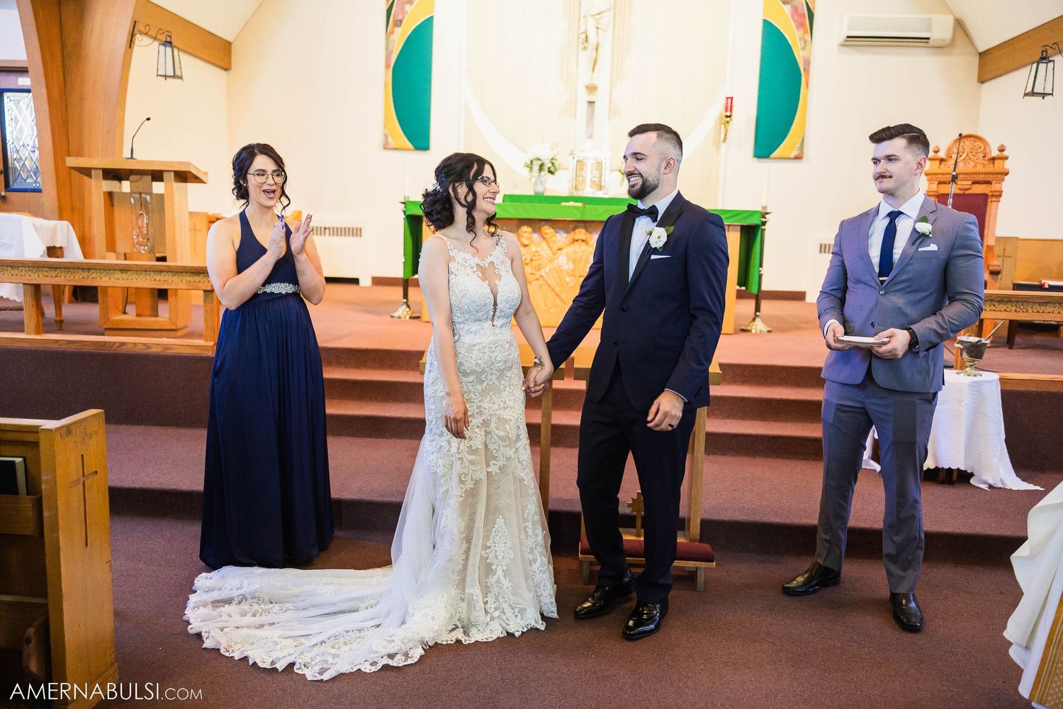 Wedding party gathered at altar in church with decorative green banners.