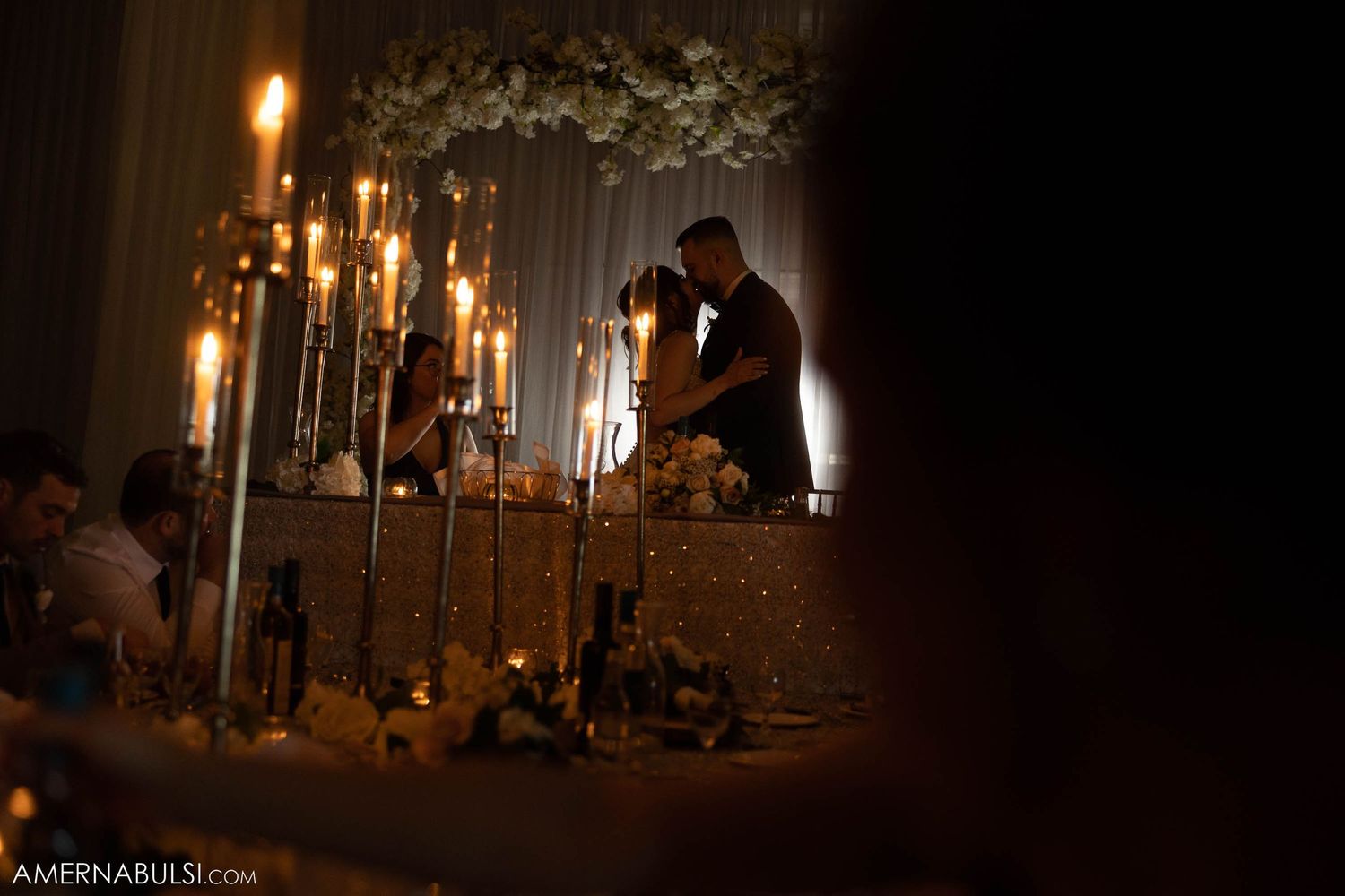 Romantic silhouette of newlyweds surrounded by glowing candles and floral decorations.