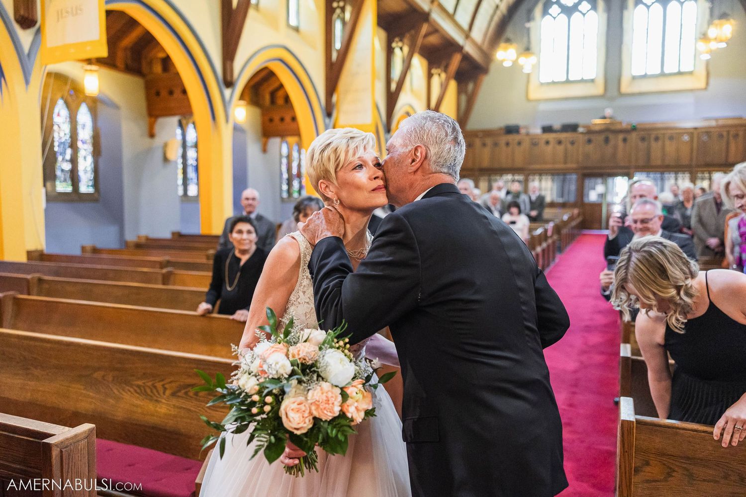 Emotional moment during wedding ceremony in historic church with yellow walls.
