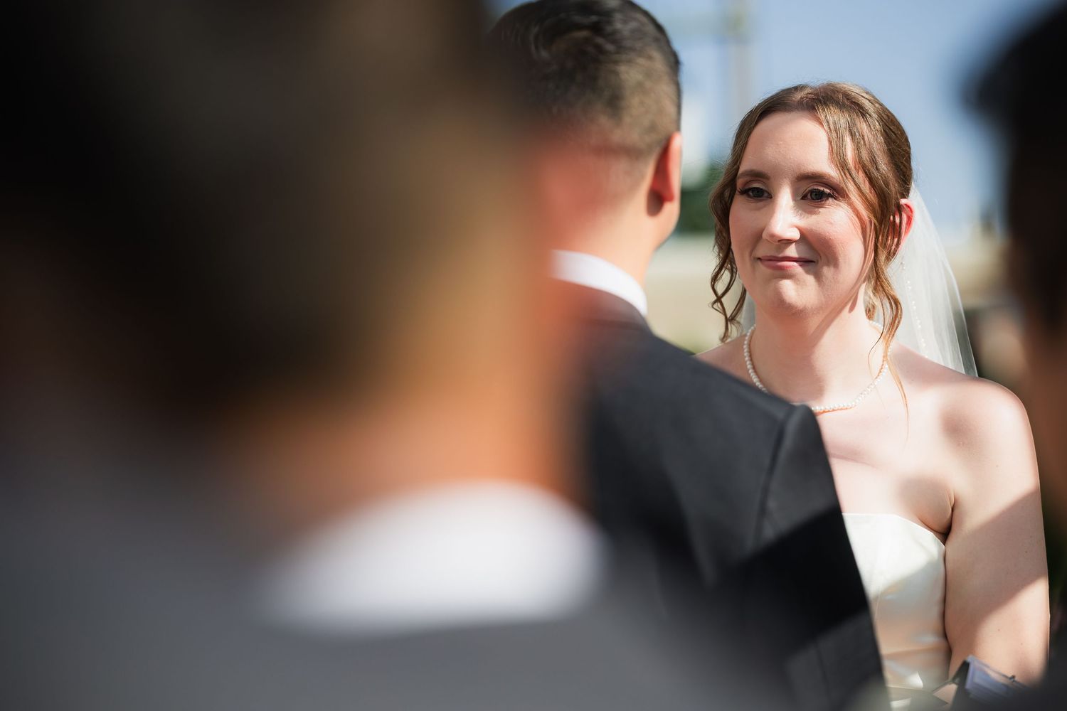 Bride smiling at groom during outdoor wedding ceremony.