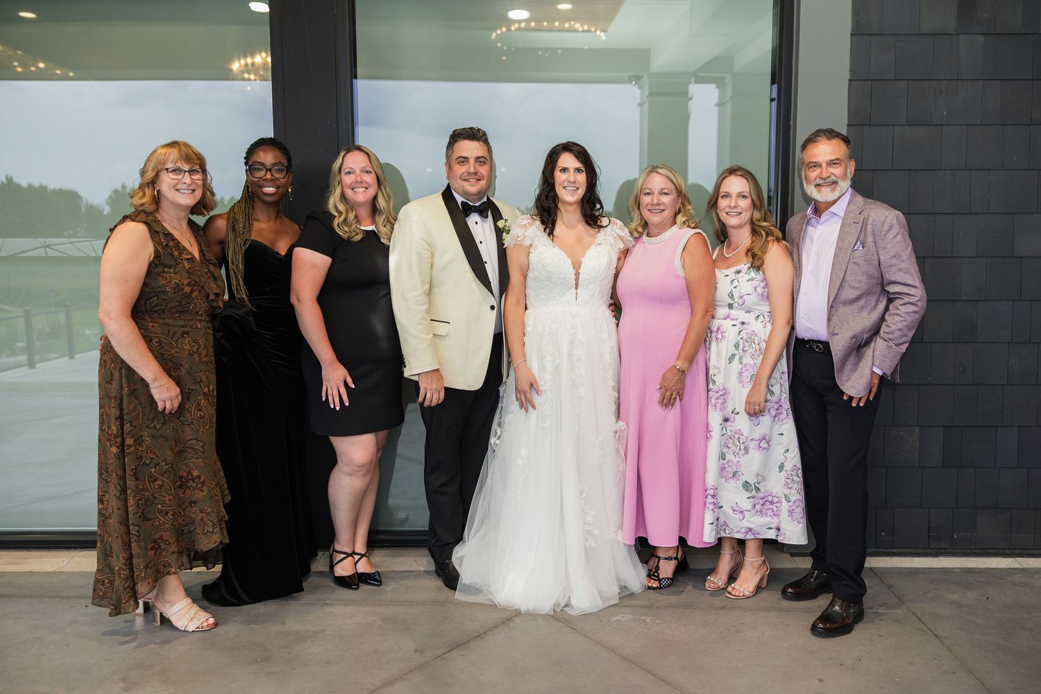 Wedding couple poses with family and friends in elegant attire at a modern venue reception.