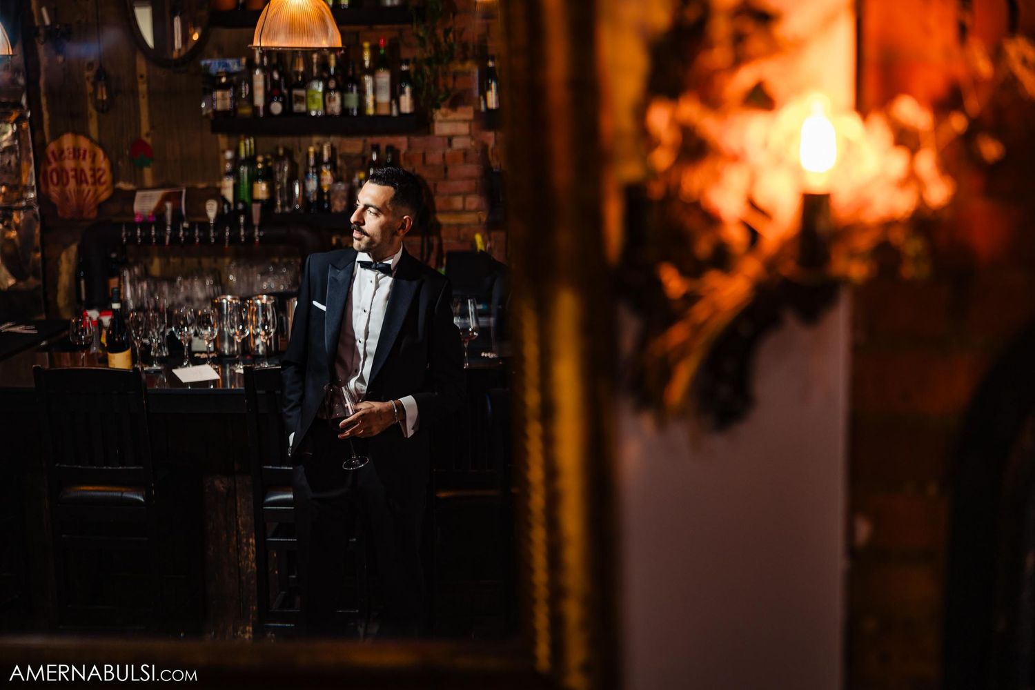 Atmospheric shot of a bar interior with warm lighting and bottles in the background.