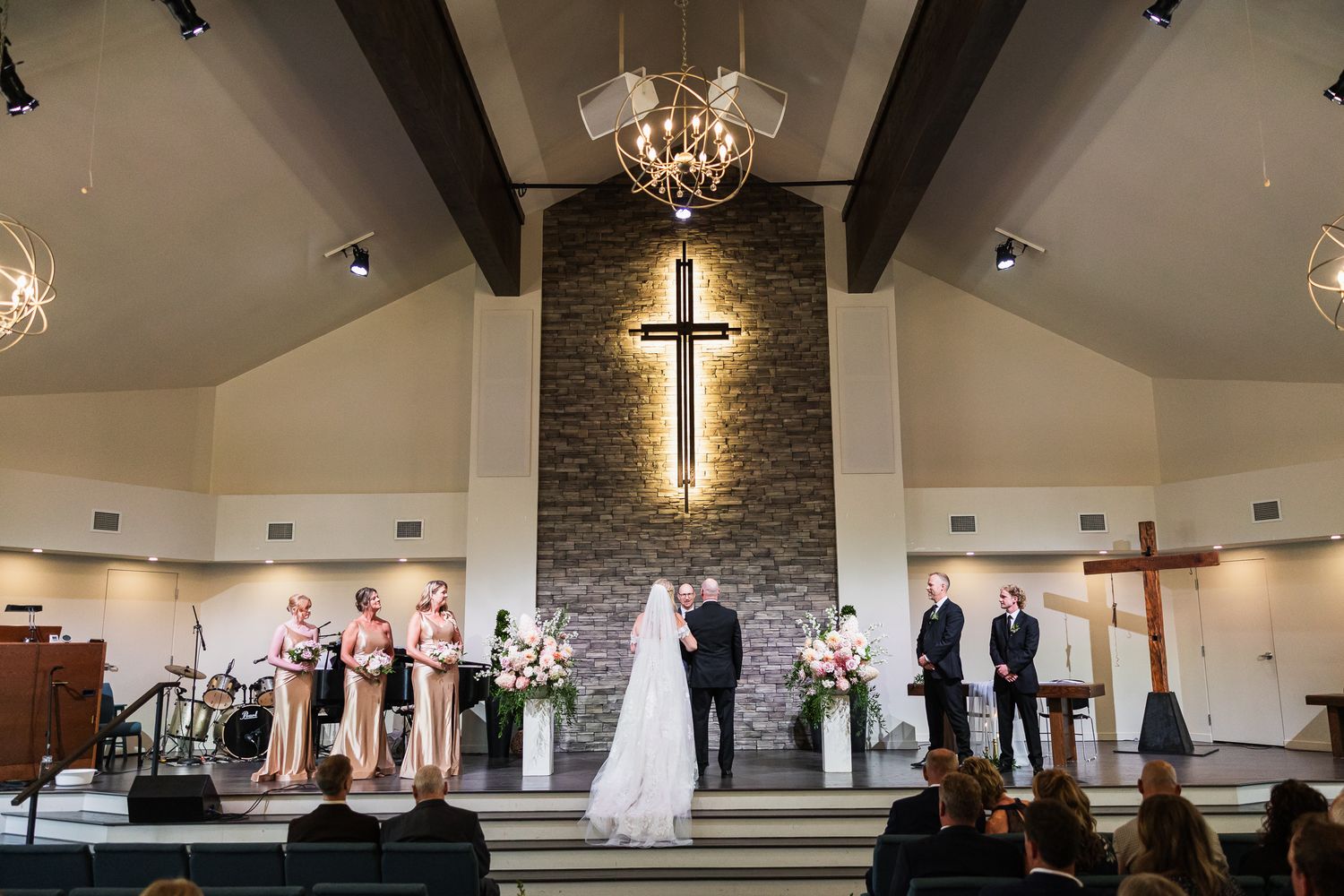 A wide angle view of modern church sanctuary with stone accent wall and wooden beams.